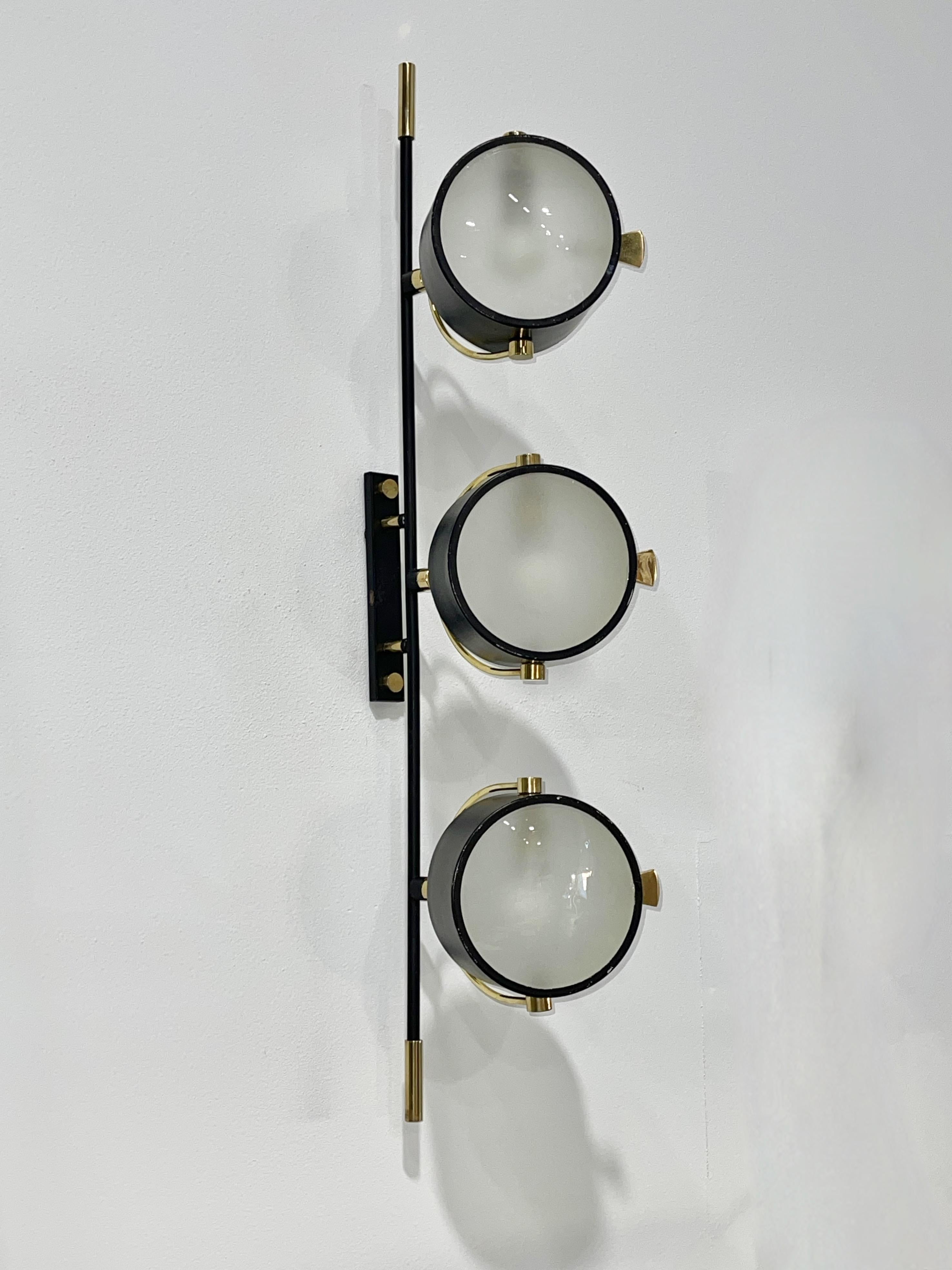 Very rare French 1950'a wall mounted fixture by Maison Lunel with three orientable circular spot reflectors with slightly convex sandblasted glass lens diffusors.  
This is part of a series offered by Lunel which included wall sconces, swing arm
