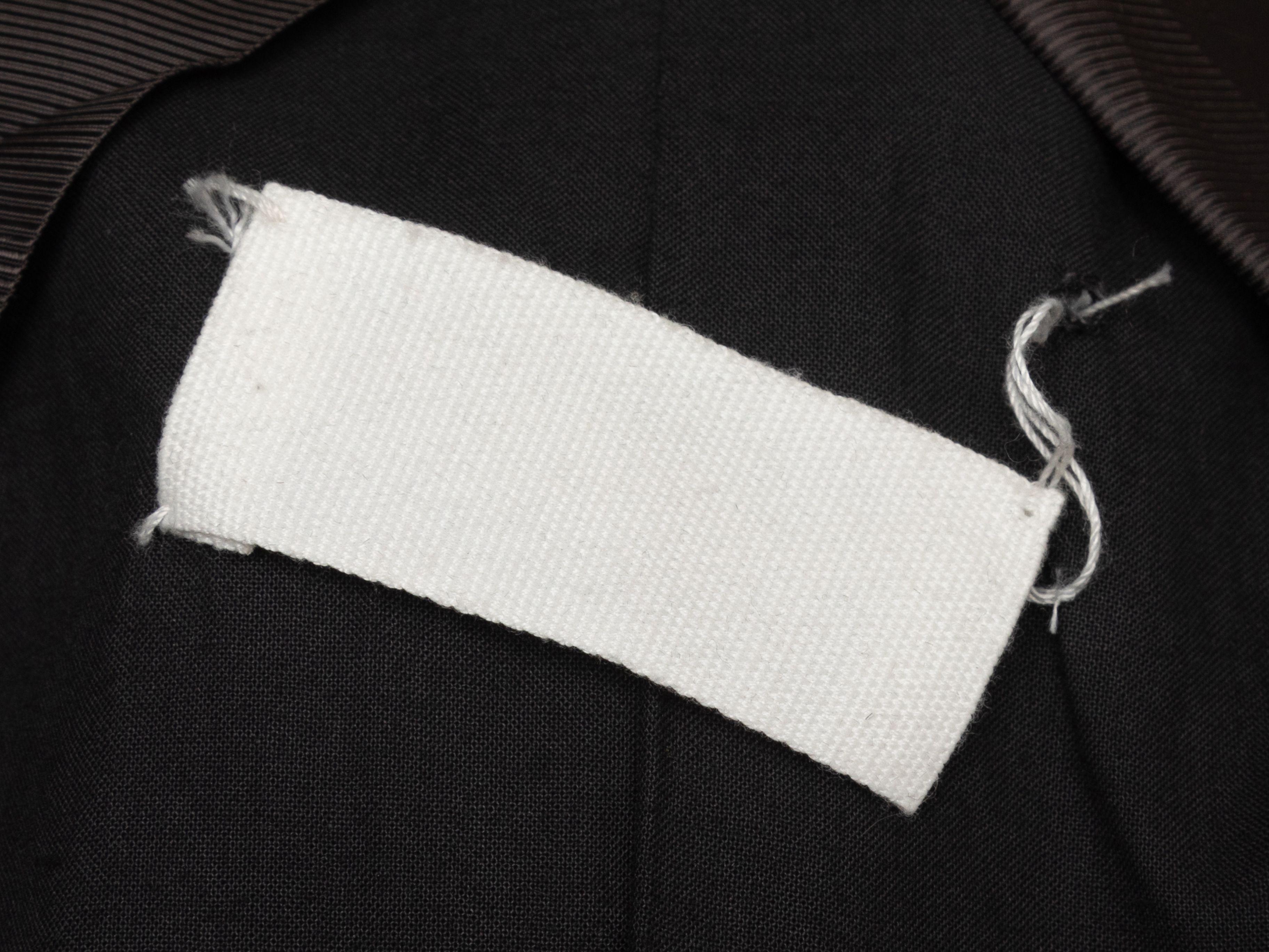 Product Details: grey longline blazer by Maison Margiela. Peaked lapel. Single welt pocket at bust. Dual flap pockets at hips. Front button closures. Designer size 42. 38