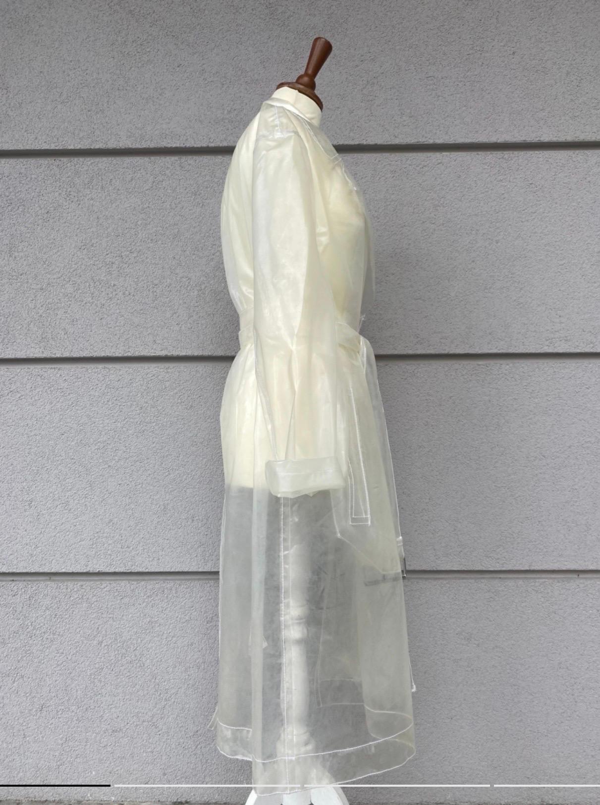 Maison Margiela MM6 Trenchcoat aus transparentem weißem Polyurethan, Größe 40, mit doppeltem Brustverschluss und Taillengürtel. Zwei Taschen auf der Vorderseite, Maße: Schulter 48 cm, Ärmel 60 cm, Brust 56 cm, Taille 60 cm, Länge 106 cm, in sehr