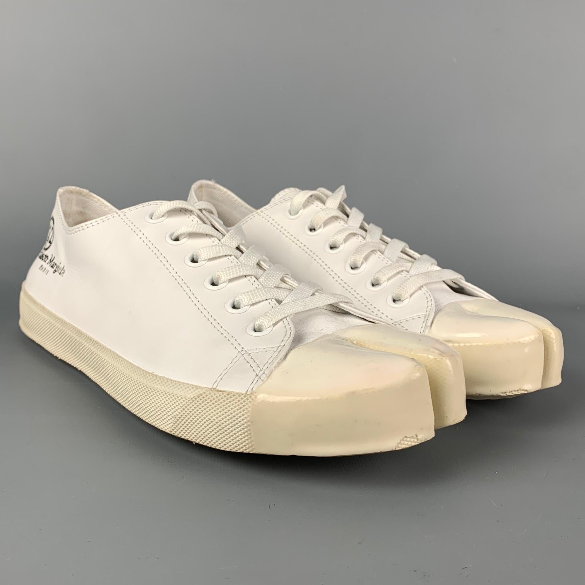 MAISON MARGIELA 'Tabi' sneakers comes in a white canvas with a patent leather trim featuring signature split toe design, rubber sole, and a lace up closure. Made in Italy. 

Very Good Pre-Owned Condition.
Marked: 44

Outsole: 12 in. x 4.25 in. 