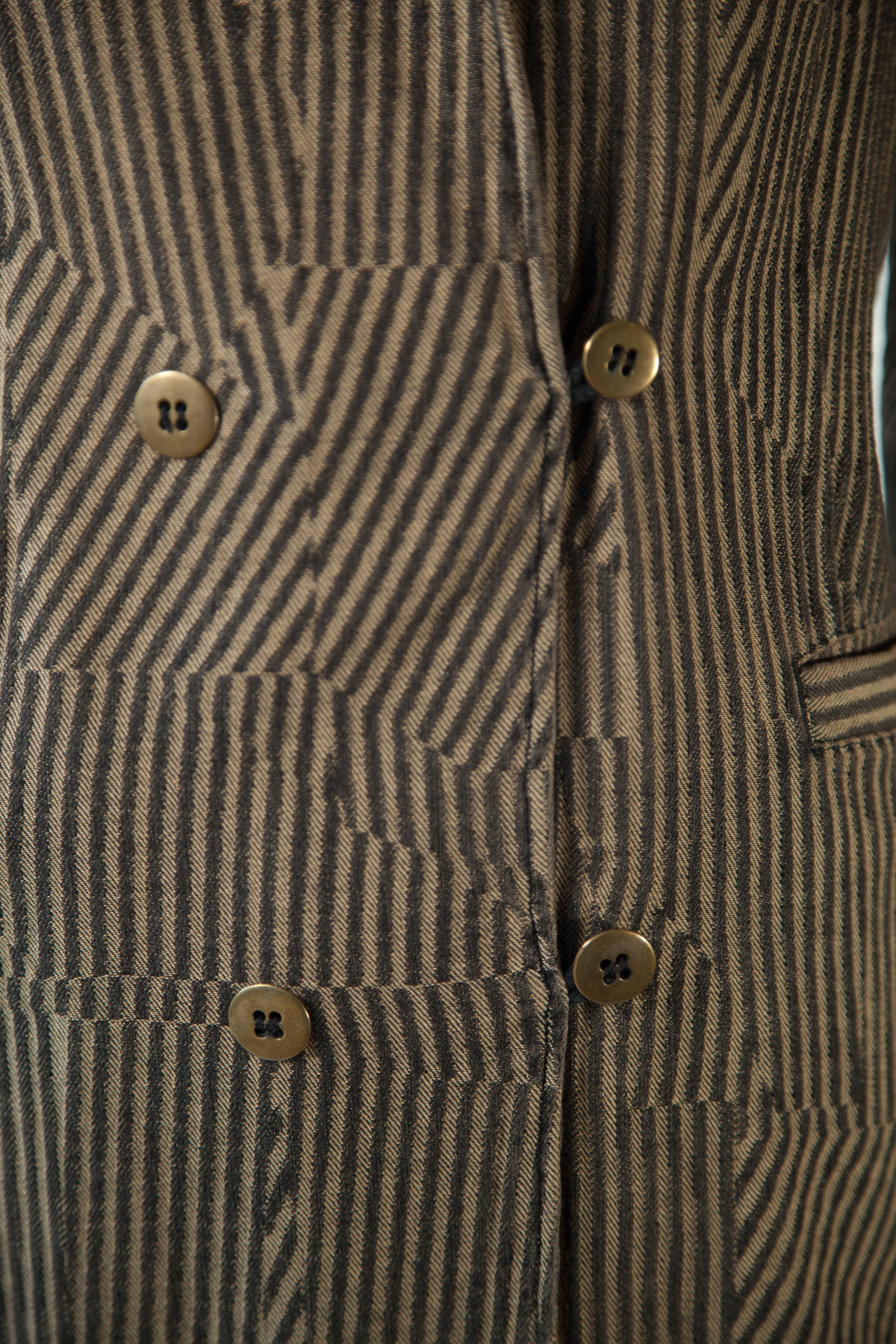 Cette veste classique de Maison Margiela est confectionnée de manière experte en 100 % coton et présente une illusion accrocheuse de rayures noires et marron allant dans des sens différents. Conçu avec une silhouette ajustée intemporelle, un col