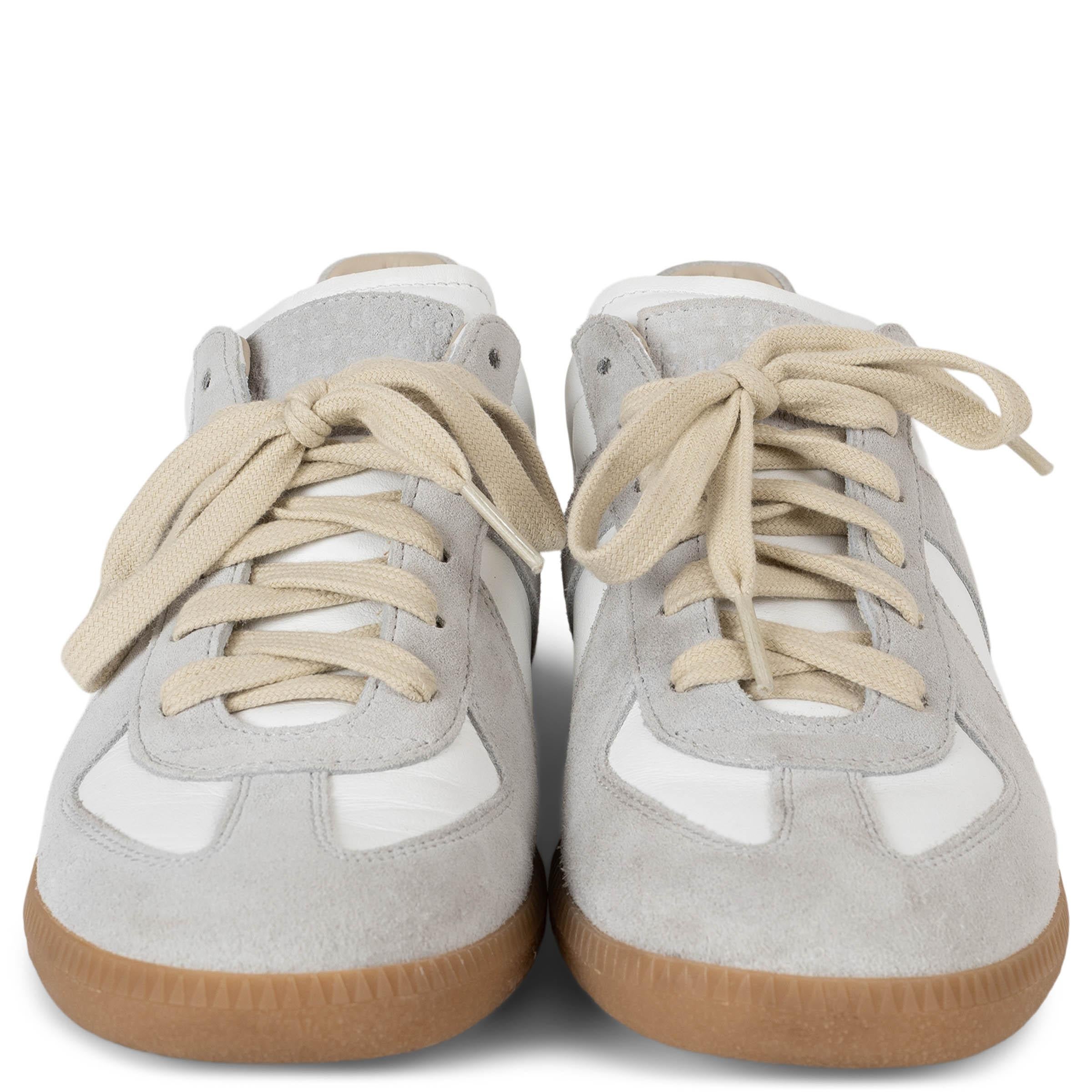 Diese 100% authentischen Maison Margiela Iconic Replica Low-Top-Sneakers aus weißem Leder mit grauen Wildlederbesätzen verkörpern die schlichte Eleganz des Hauses. Mit ihrer abgerundeten Zehenpartie, den cremefarbenen Schnürsenkeln und der