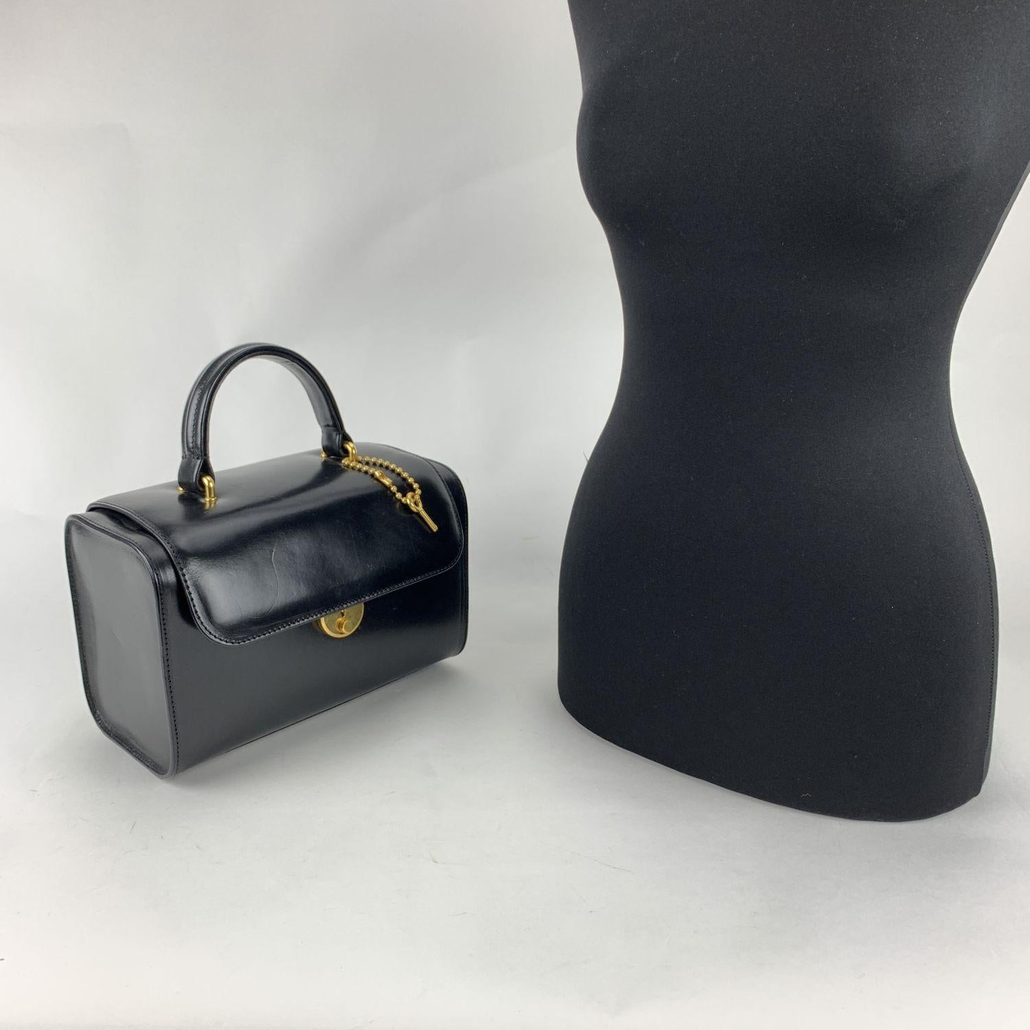 Maison Martin Margiela box-shaped 'Replica Bag' in black leather. The bag is a reproduction of a Travel beuty case design of the '70s. It features a key lock closure, 4 protective bottom feet, a top carry handle and a removable shoulder strap. 1