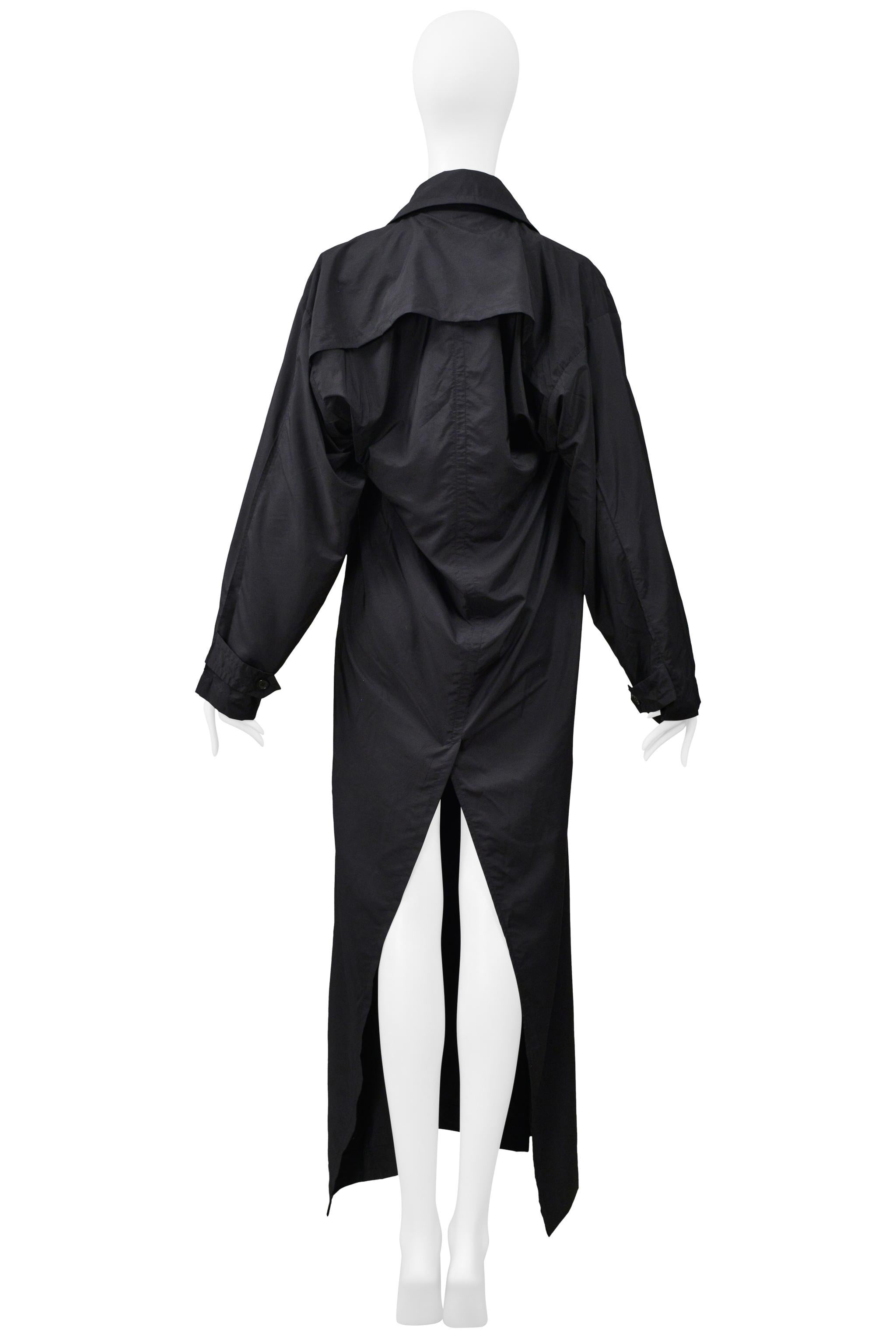 Resurrection Vintage a le plaisir de vous proposer un imperméable vintage en tissu technique noir brillant de la Maison Martin Martine, avec une patte de boutonnage cachée, des poches latérales et une profonde fente centrale dans le dos.

Maison