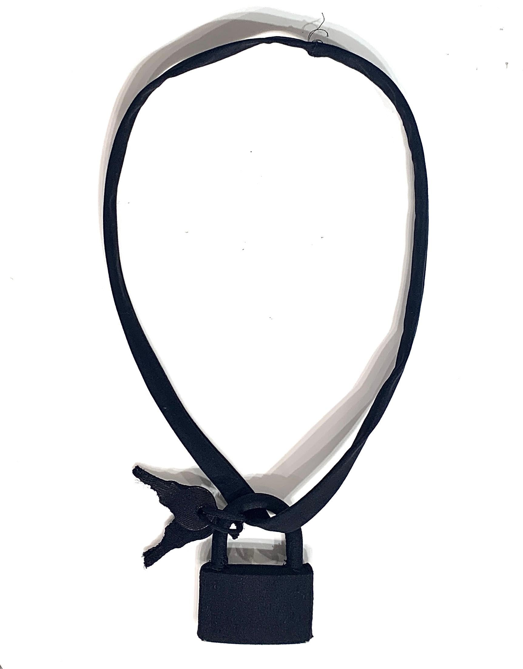 Le collier de Maison Martin Margiela pour la saison automne/hiver 2007 se compose de mèches recouvertes de tissu élastique, l'une de couleur chair et l'autre noire. 
Le cadenas et les clés sont d'origine, en métal et en laiton.
Le couvercle
