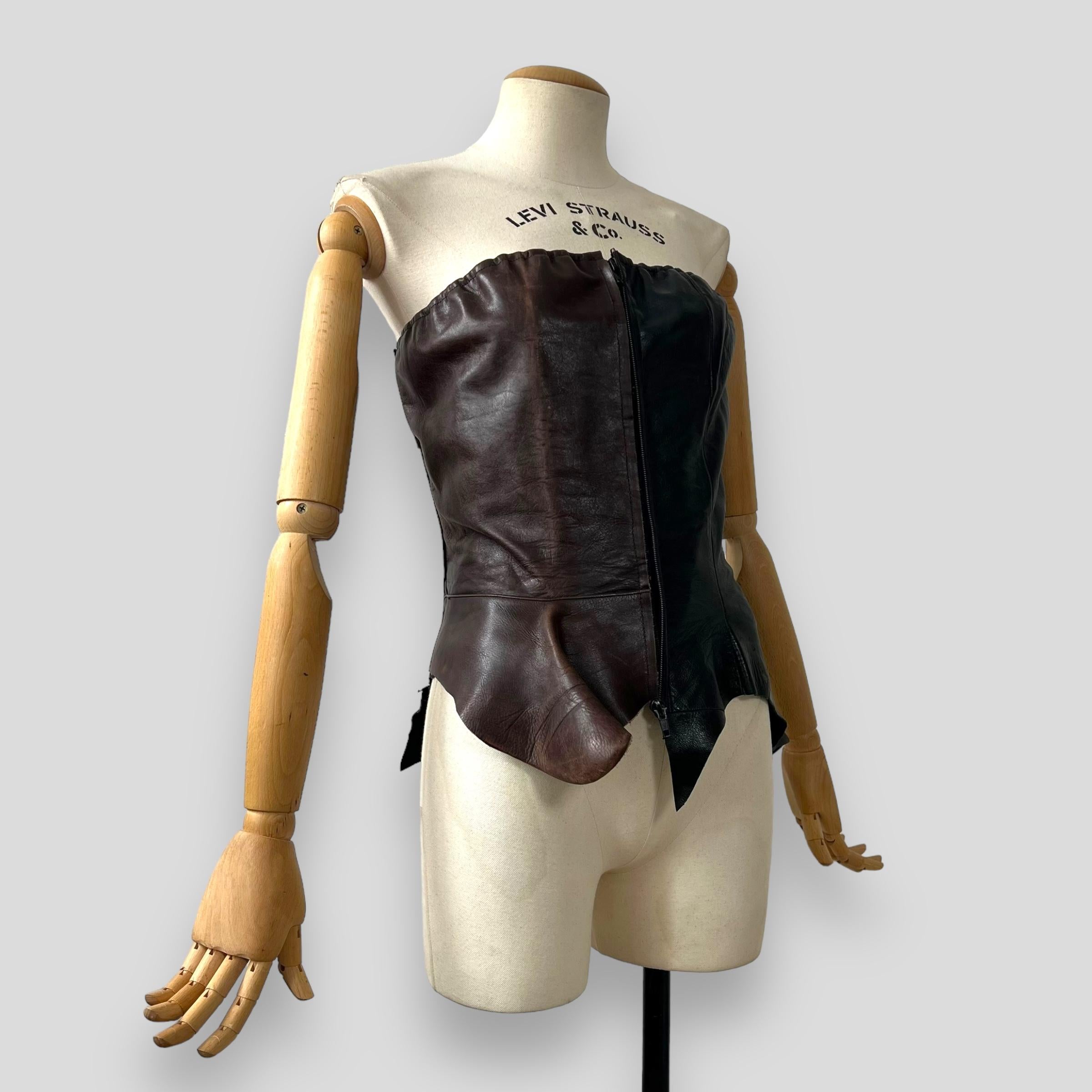 The Maison Martin Margiela Artisanal Fall-Winter 2004-2005 Collection includes a corset from brown and black leathers crafted from repurposed vintage boots. This corset features a front zipper, is fully lined, and is sized IT 42. The leather's
