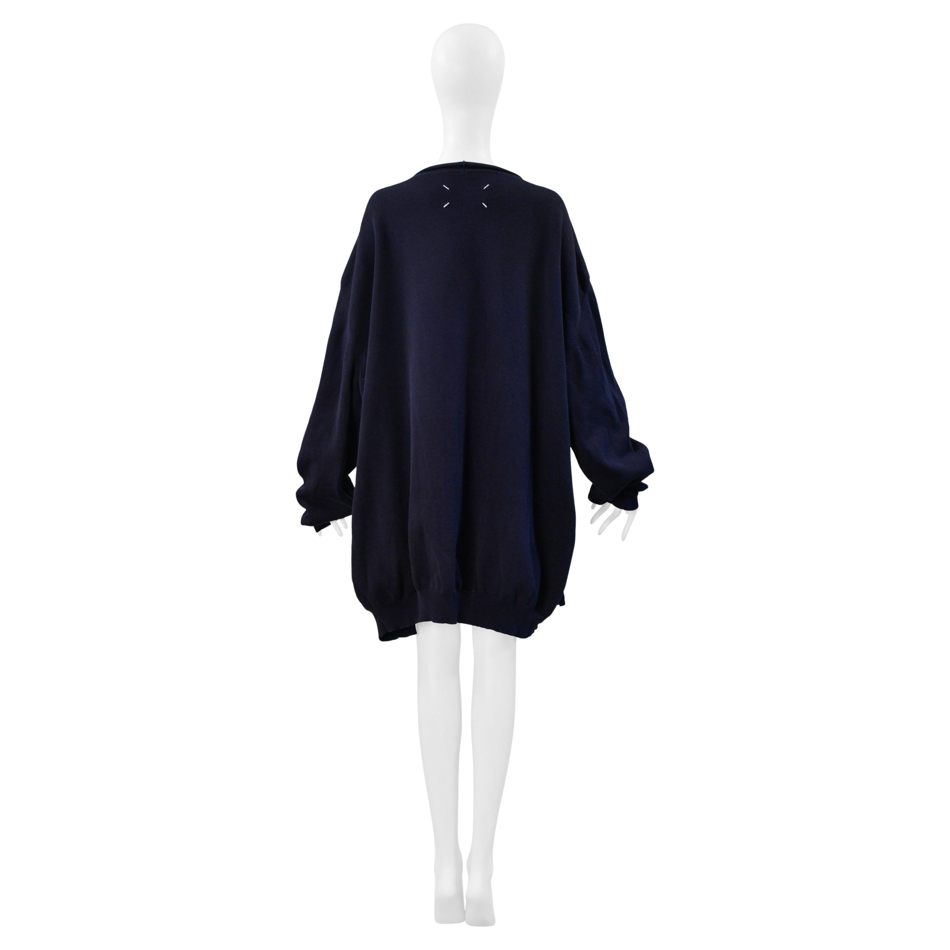 Resurrection Vintage freut sich, einen marineblauen Oversize-Pullover von Maison Martin Margiela aus der Kollektion 2000 anbieten zu können. Er hat verlängerte Ärmel, einen Knopfverschluss vorne und zwei Taschen vorne. Dieses Stück ist sowohl für