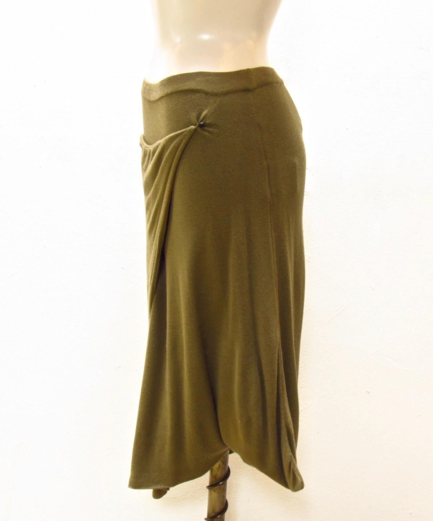 This soft rayon knit skirt comes in an earthy olive color from Maison Martin Margiela. The faux wrap front secures with a small button. 