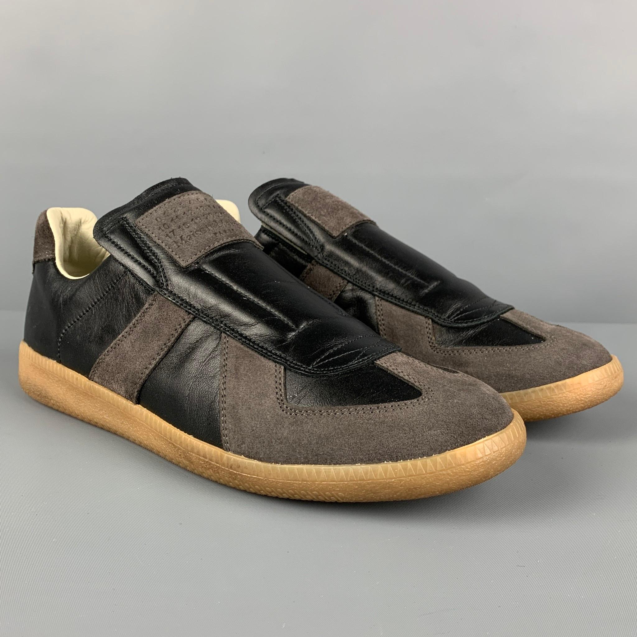 MAISON MARTIN MARGIELA 'Replica' sneakers comes in a black & grey color block leather featuring a slip on and a rubber sole. Made in Italy. 

Very Good Pre-Owned Condition.
Marked: 41

Outsole: 11 in. x 3.5 in. 