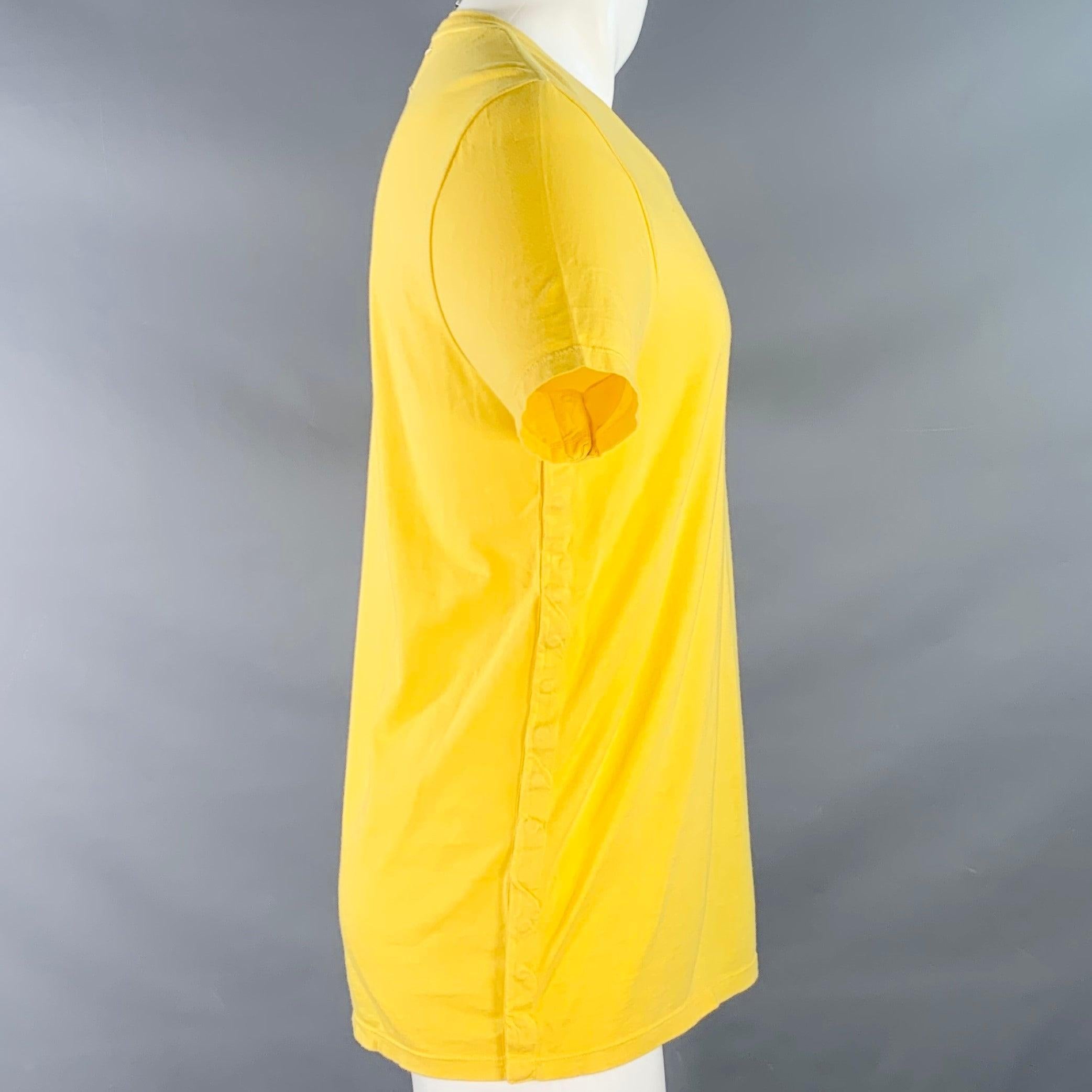 T-shirt MAISON MARTIN MARGIELA
en jersey de coton jaune, avec des boutons-pression sur les côtés, des manches courtes et un col ras du cou. Fabriqué en Italie. Bon état d'usage. Boulochage modéré, multiples marques mineures. En l'état. 

Marqué :  