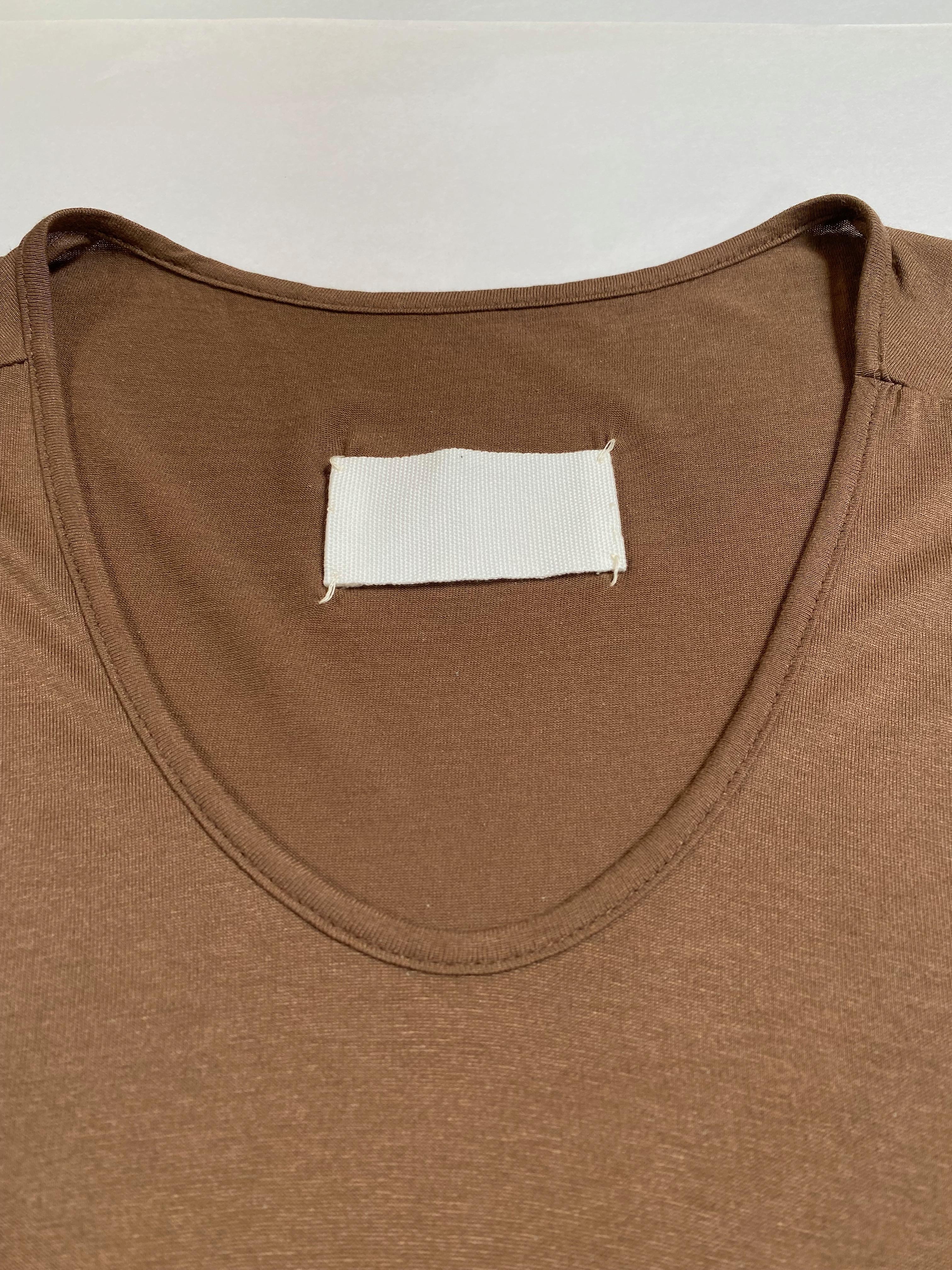 A unique light brown soft jersey sleeveless top features an asymmetrical hem, longer in front with softly draped shorter back. Cotton top comes from Maison Martin Margiela Iconic Collection.
