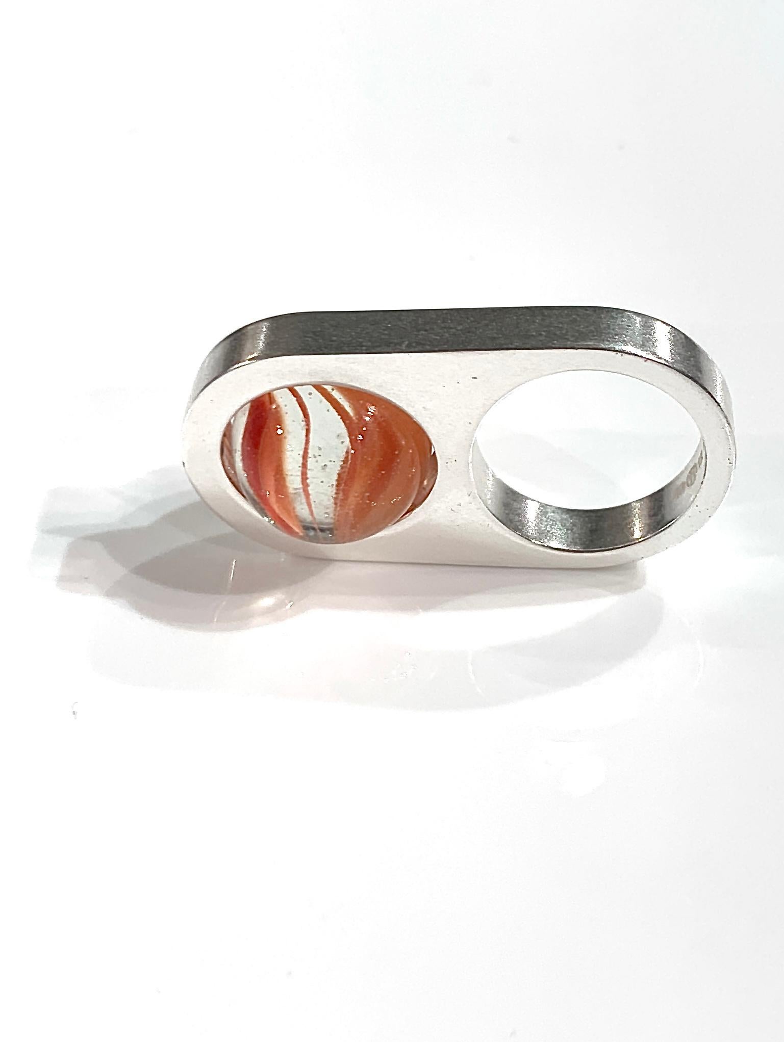 Maison Martin Margiela ring  of the summer 2016 season with a colored glass marble embedded inside a brass structure. 
The marble can spin on itself. Inside the ring is the brand's numerical mark, with the circled 11 indicating the unisex