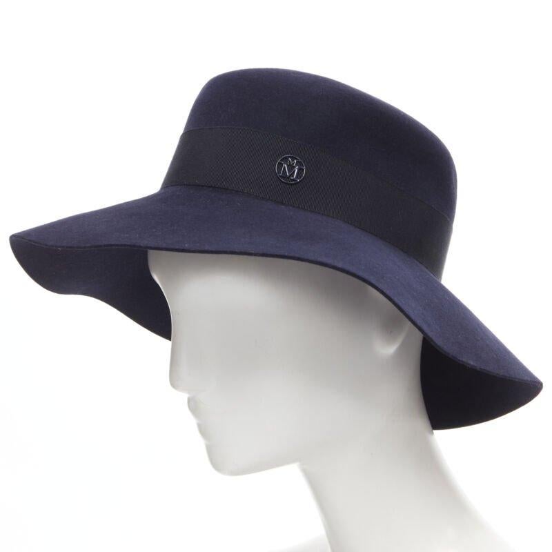 MAISON MICHEL navyblau schwarz grosgrain M Logo Detail Fedora Hut S 56cm
Referenz: MELK/A00157
Marke: Maison Michel
MATERIAL: Wolle
Farbe: Marineblau
Muster: Solide

ZUSTAND:
Zustand: Ungetragen in neuwertigem Zustand, mit Etiketten. 
Kommt mit: