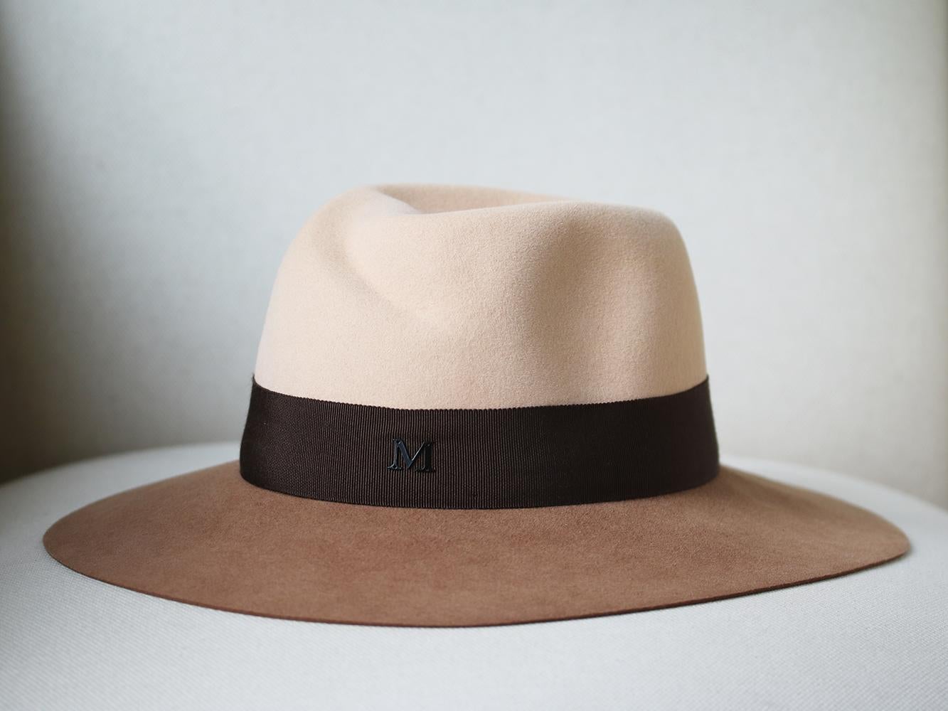 Couture millinery, Maison Michel, is renowned for its expert craftsmanship. This two-tone rabbit-felt fedora is impeccably constructed by hand and fitted with an elasticated internal brow band. The chocolate grosgrain trim is adorned with a metal