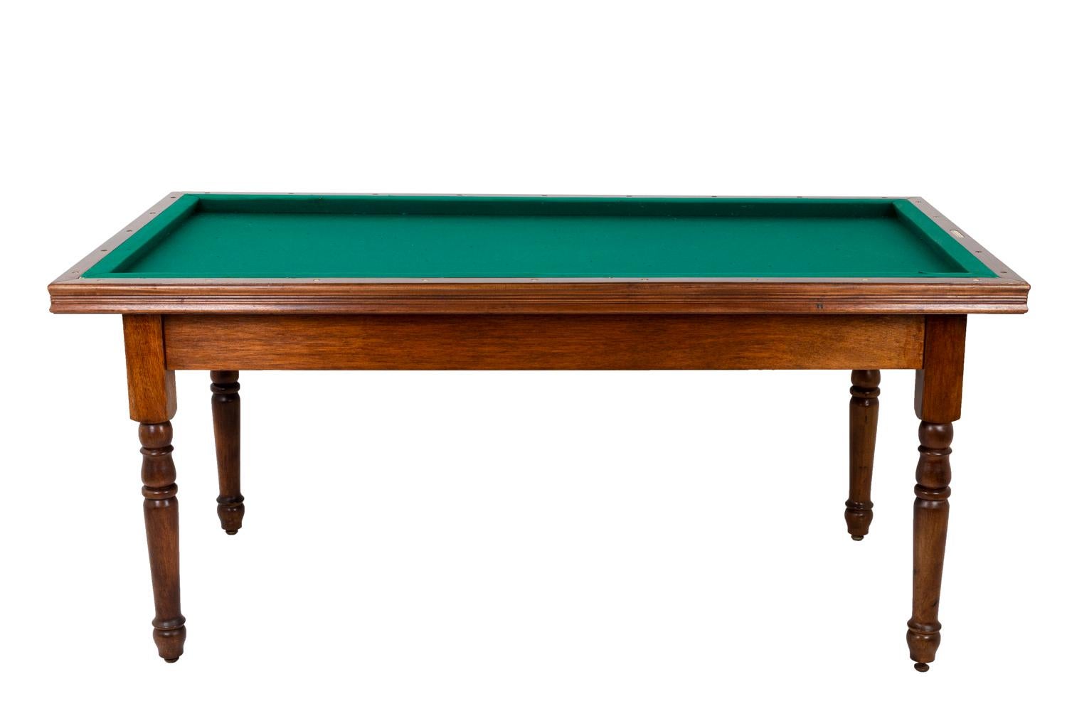 Maison Philippe Malige, signed.

Louis-Philippe style French billiard table in mahogany standing on for straight molded legs. Tray in green fabric, removable and reversible in order to transform it into a table. Four cues and three balls stored