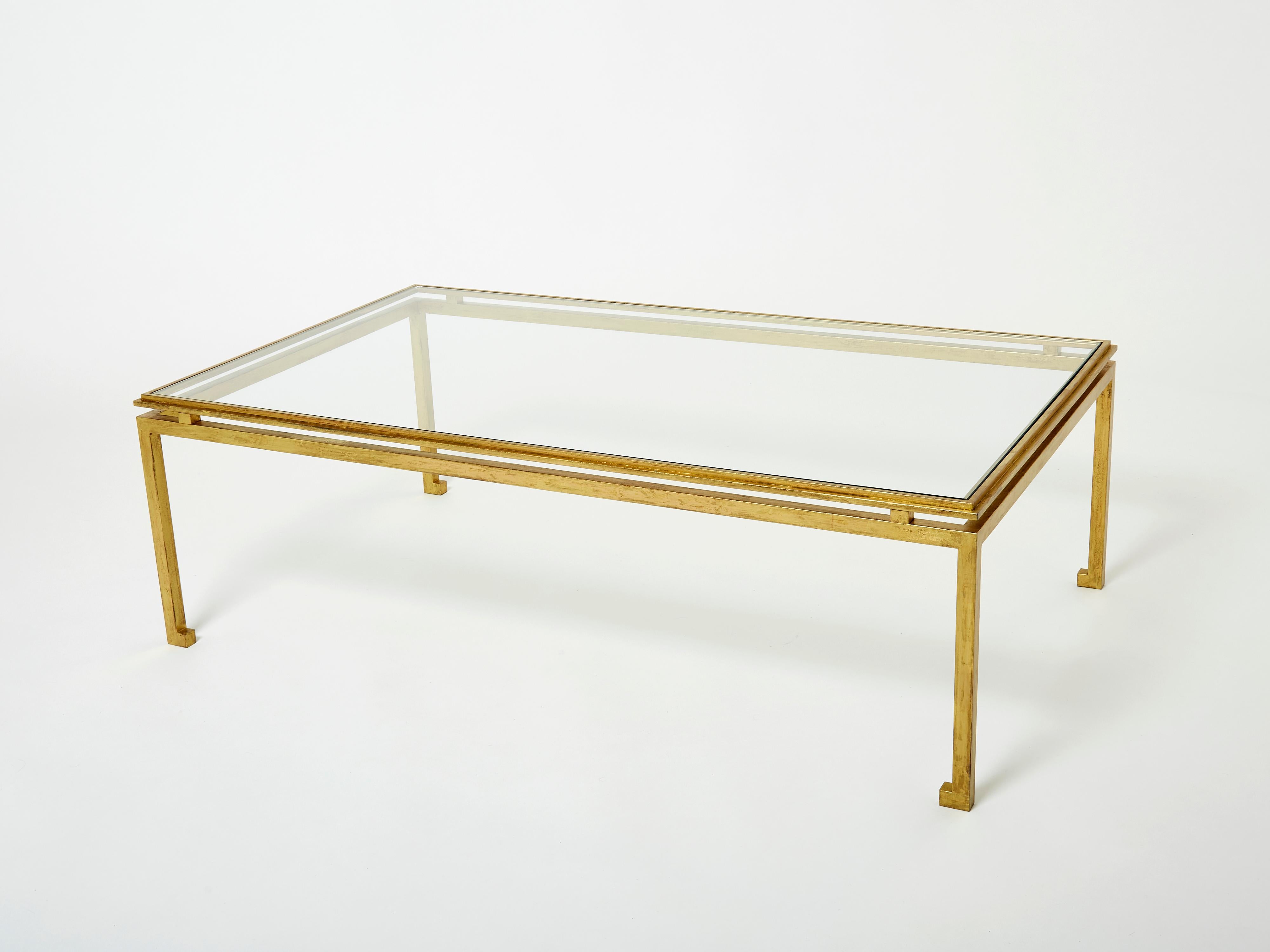 This beautiful coffee table by Maison Ramsay is from the 1950s, and carries with it the elegant mood of the neoclassical post art deco period. The wrought iron feet are glittering in an antiqued gold gilt finish, while the transparent glass top