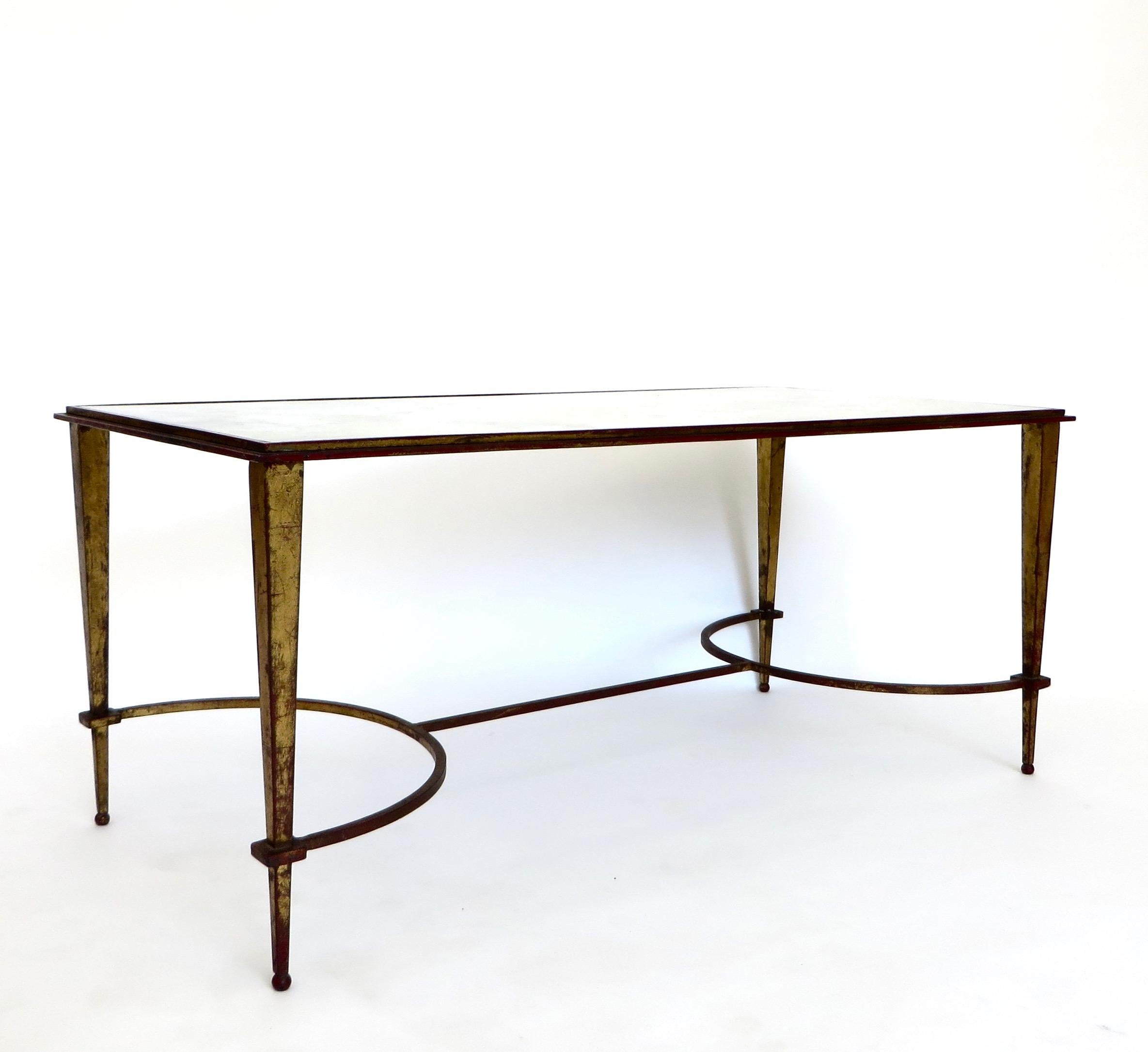 Maison Ramsay patinated gilded iron base with mirrored glass top.
The gilded legs have a tapered shape and are connected by a thin stretcher. 
The mirrored glass plateau top is in beautiful condition with cloud like verre eglomise or gold mirroring,