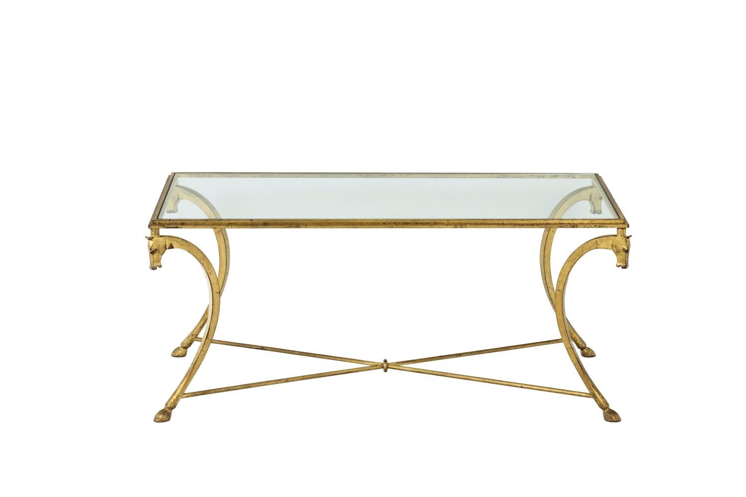Jean-Charles Moreux for Maison Ramsay, in the style of.

Rectangular coffee table in gilt iron standing on four curved legs stylized as horse head and hoof connected by two X-shaped spacers. Tray in glass.

Work realized in the 1950’s.