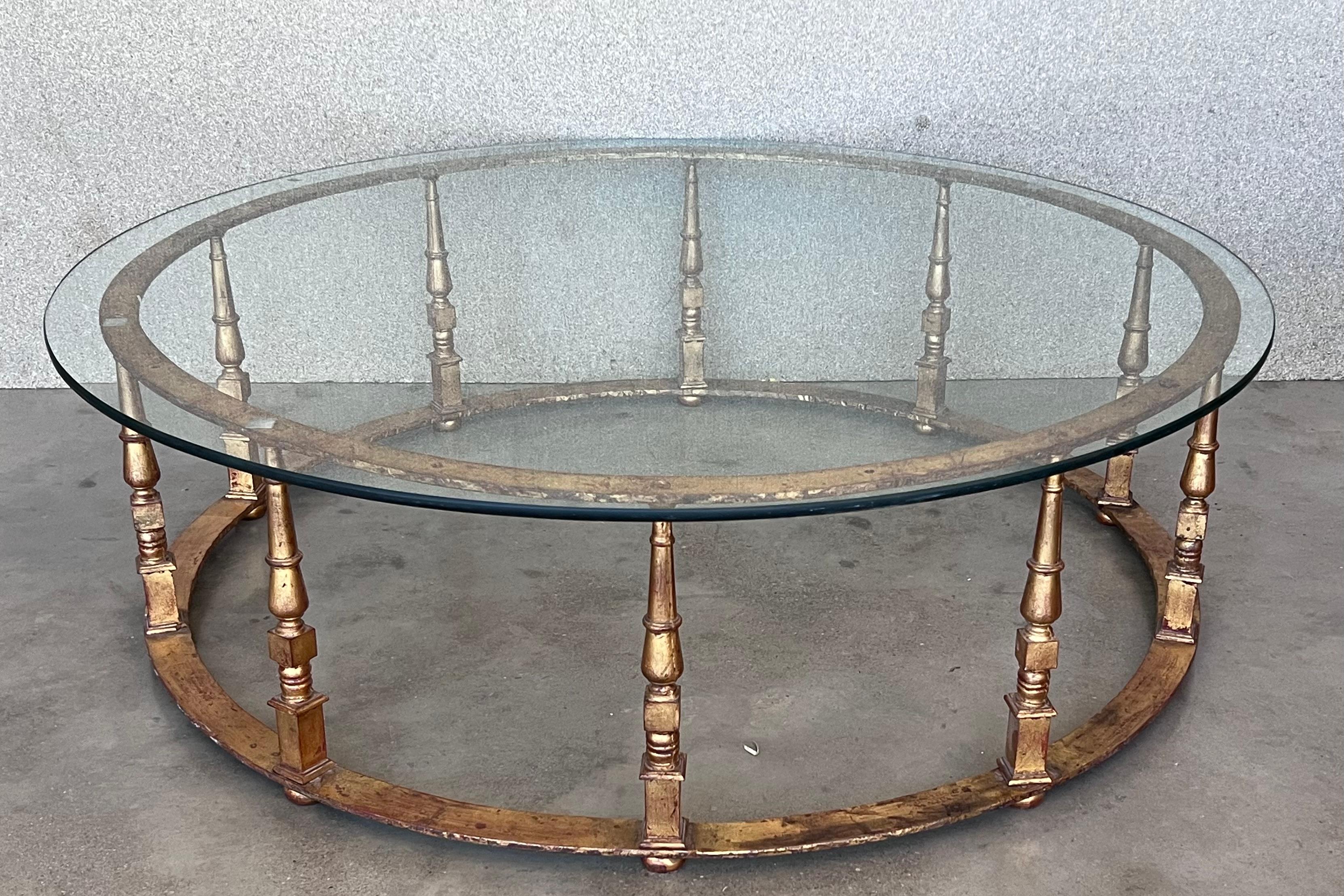 Round coffee table in the style French Maison Ramsey with hammered forged iron structure, shaped legs patinated with gold leaf finishing, The top glass is thick and the end of the legs are placed on a solid balls. 
The table are very heavy and