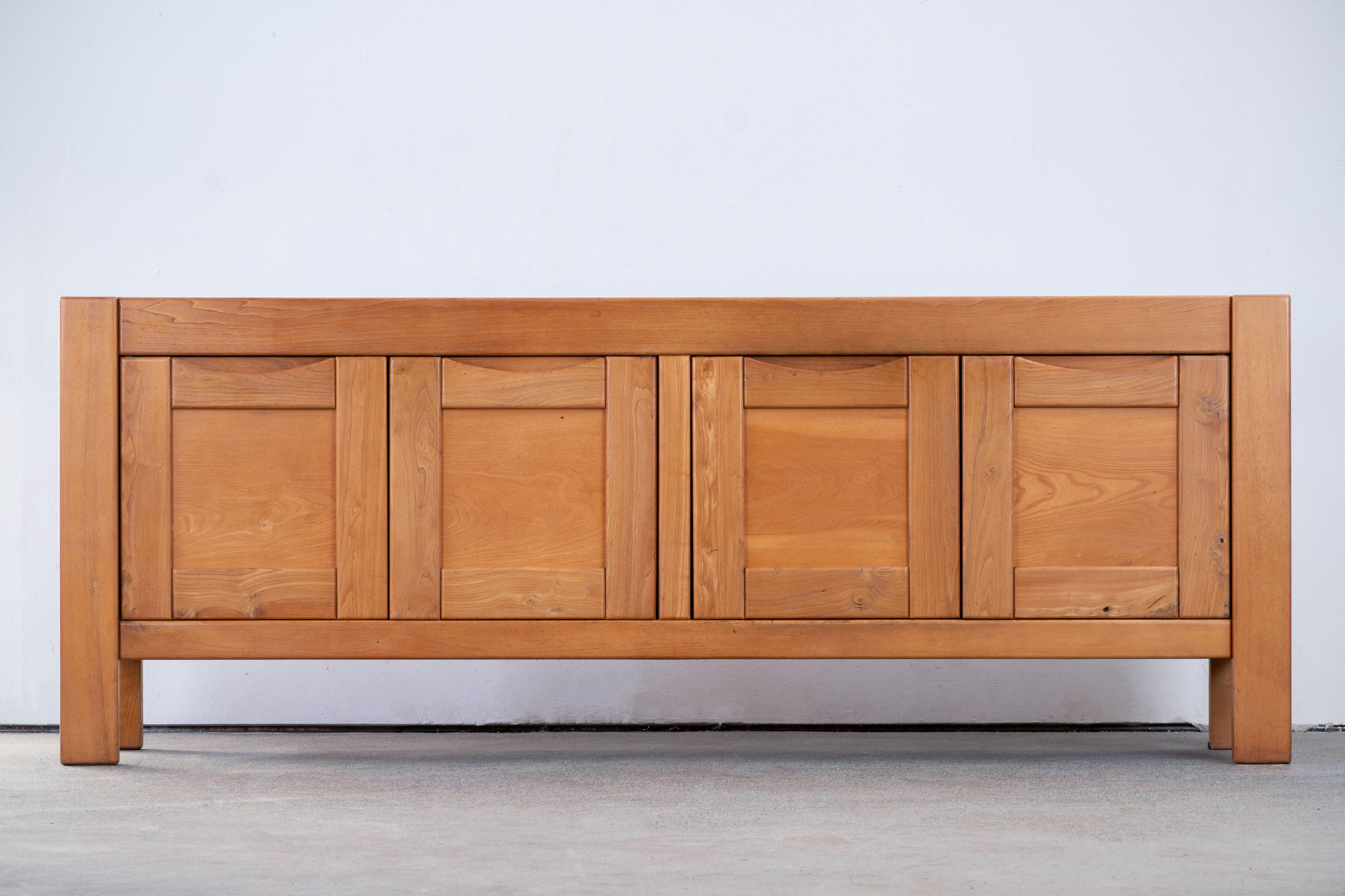 This impressive sideboard is attributed at Maison Regain, France in the late 1970s. The sideboard is made in solid elmwood and has a double door on the left with two beautifully crafted, sculptural handles. A convenient flap style opening and three
