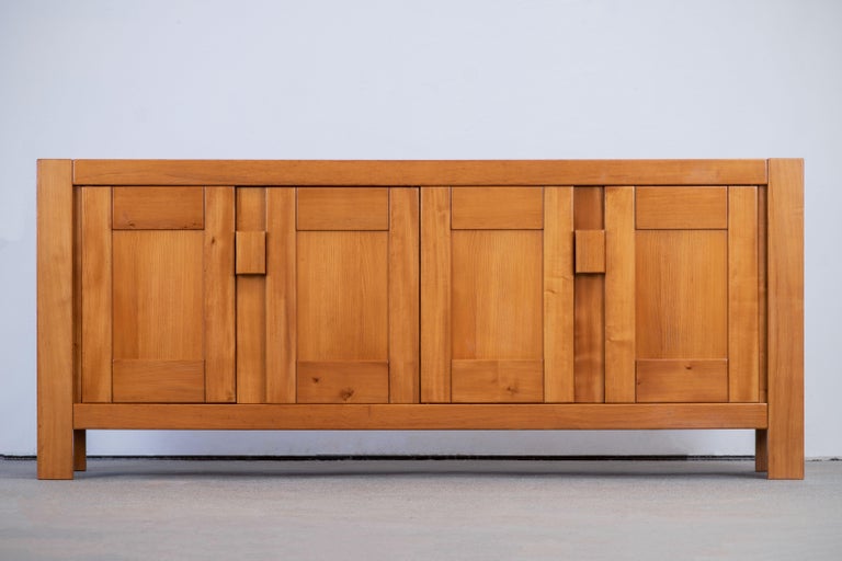 This impressive sideboard is attributed to Maison Regain, France in the late 1970s. The sideboard is made in solid elmwood and has a double door on the left with two beautifully crafted, sculptural handles. A convenient flap style opening and three