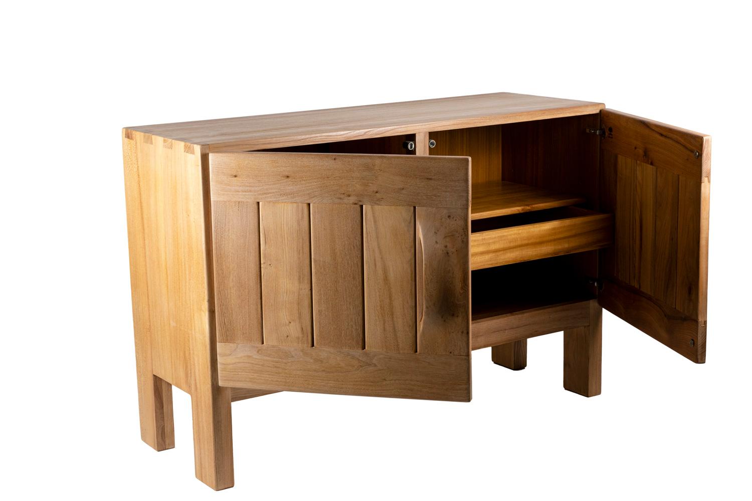 Maison Regain, signed. Pierre Chapo, in the style of. 
Buffet in natural elm opening by two-door leaves on two compartments with one shelf and one drawer. It stands on four straight legs. It is composed by raw battens. Handles carved inside the