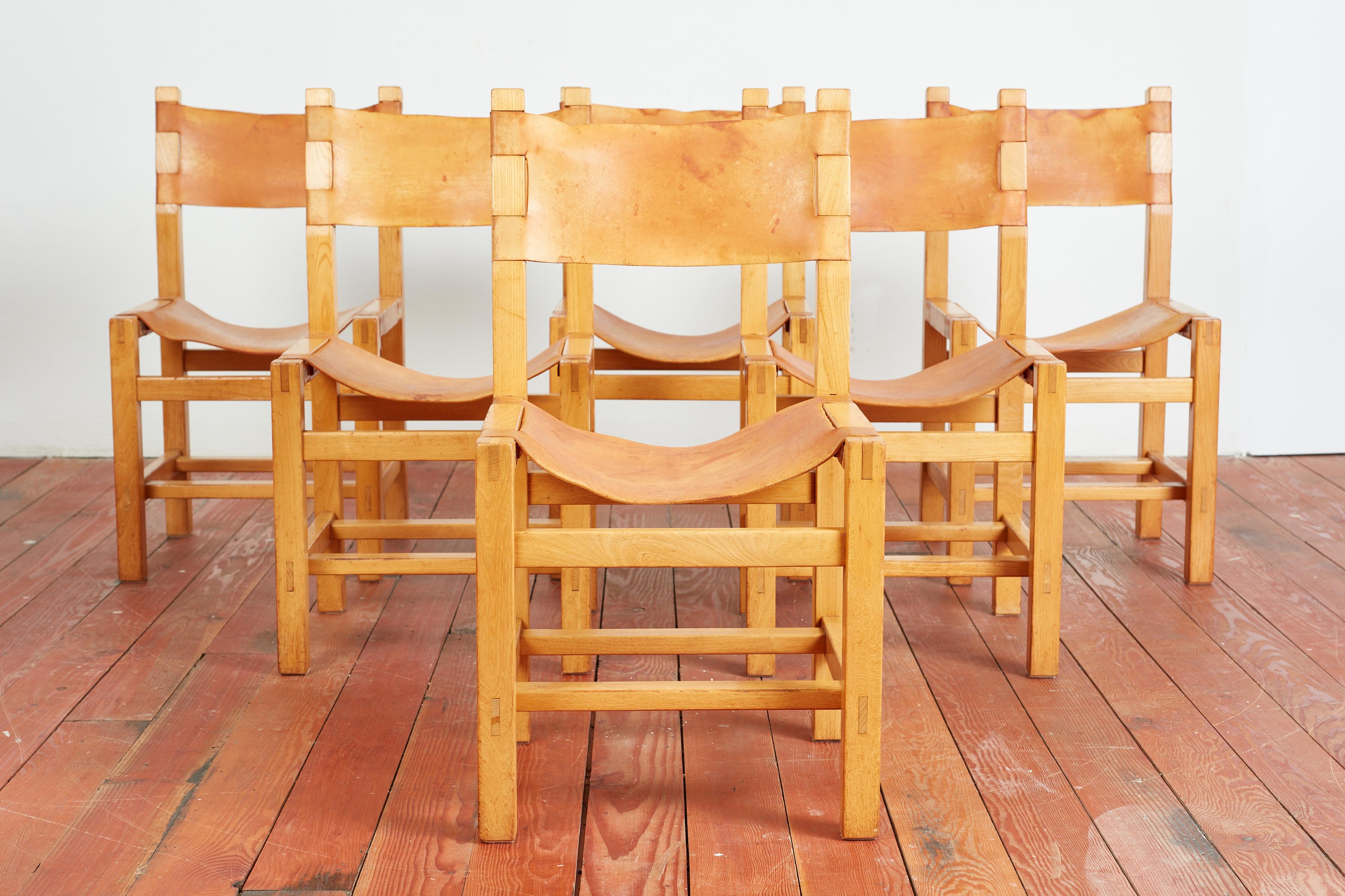 Maison Regain dining chairs  - set of 6 
France, 1960s
Signature leather sling seats and backs with wood frames - great joinery 
In the style of Pierre Chapo with wonderful patina to leather. 
These chairs nice detailing of metal hardware on the