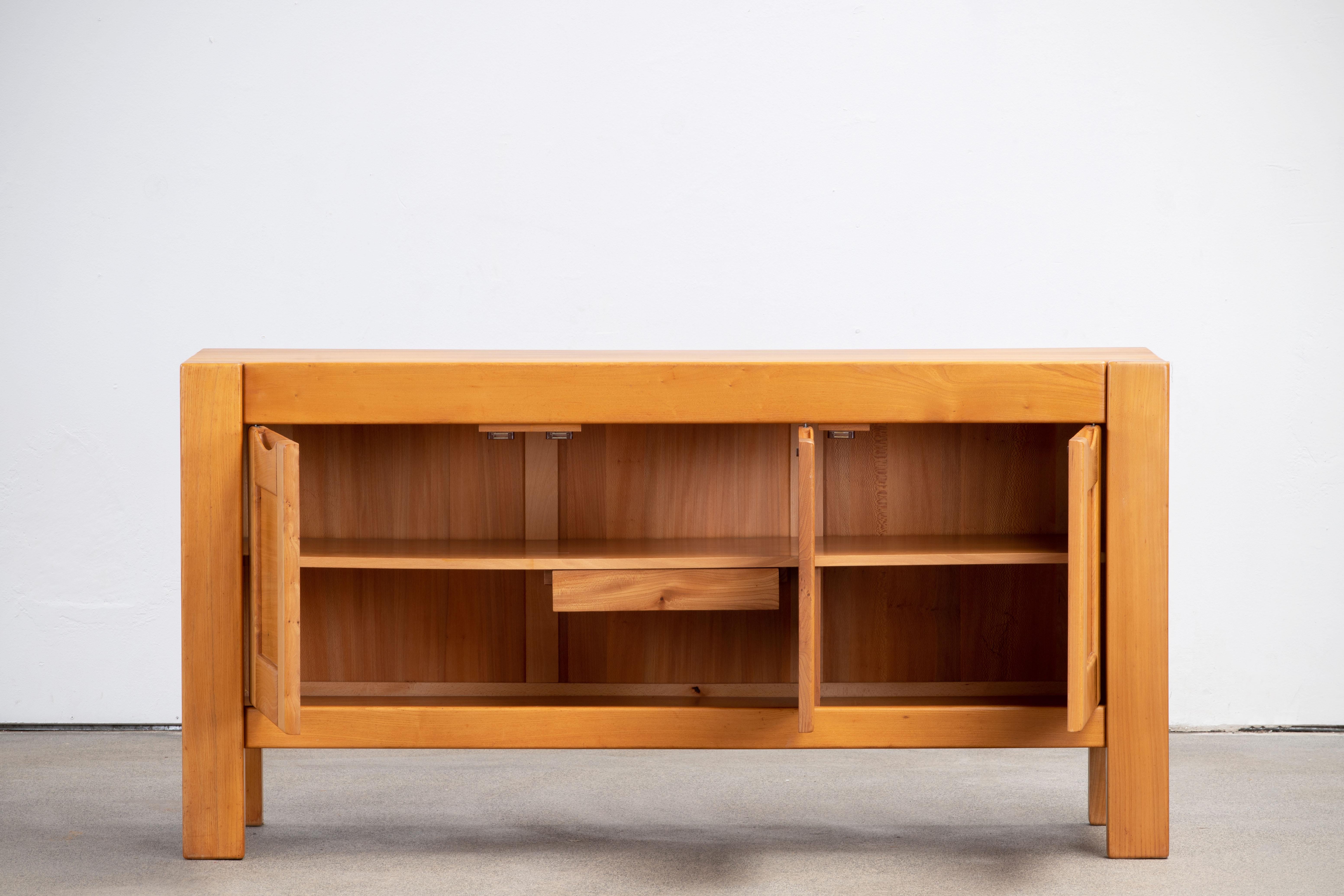 This impressive sideboard is attributed at Maison Regain, France in the late 1970s. The sideboard is made in solid elmwood and has a double door on the left with two beautifully crafted, sculptural handles. 
The wooden connections on the top, the