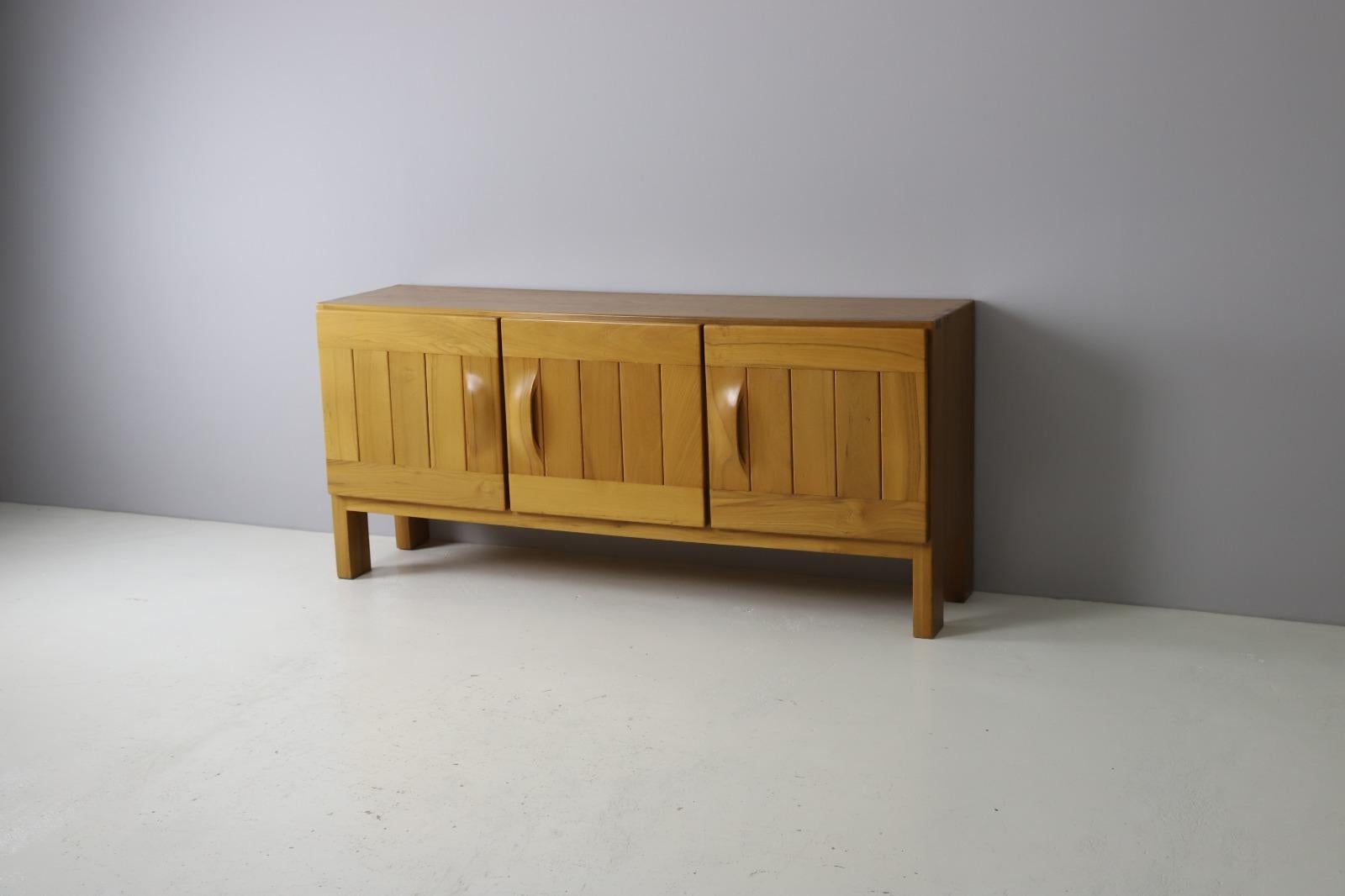 Large French sideboard produced by Maison Regain in solid elm wood. The finger joints on both upper corners and the large solid wood door pulls are very typical for Maison Regains designs and craftsmanship. The heavily made doors give you access to
