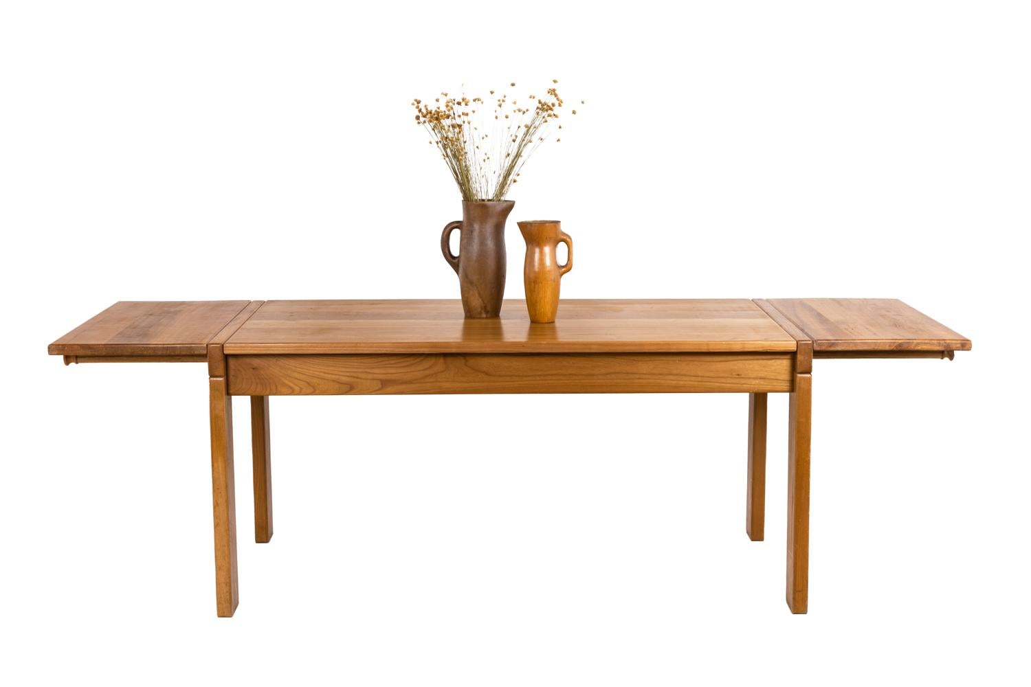 Maison Regain, attributed to.

Rectangular shape dining table in blond elm. Composed of four rectangular-shaped feet linked by four high studs including two small removable ones allowing the installation of extensions. The elm top is embedded in