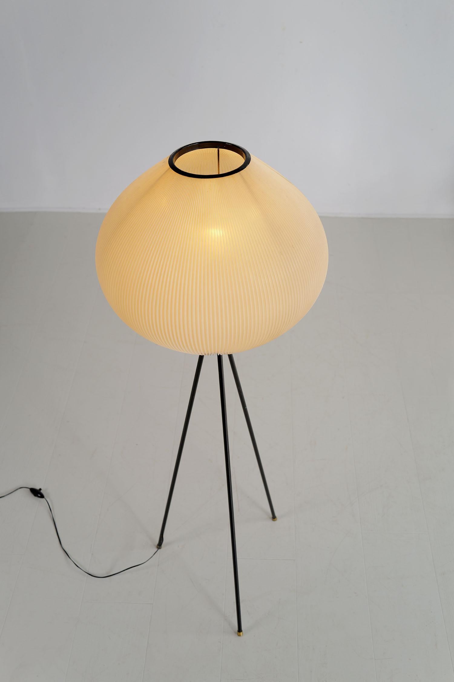 Rara lámpara de pie japonesa de Maison Rispal, Francia 1960. La base trípode de metal tubular lacado en negro está realzada por almohadillas de latón dorado; la pantalla rodoide plisada está fijada a un casquillo de bayoneta. La delicadeza del