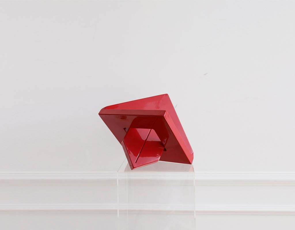 Skulptur mit rotem Pfeil. Die Geometrie umhüllt einen Raum mit einem Verlust an Harmonie.