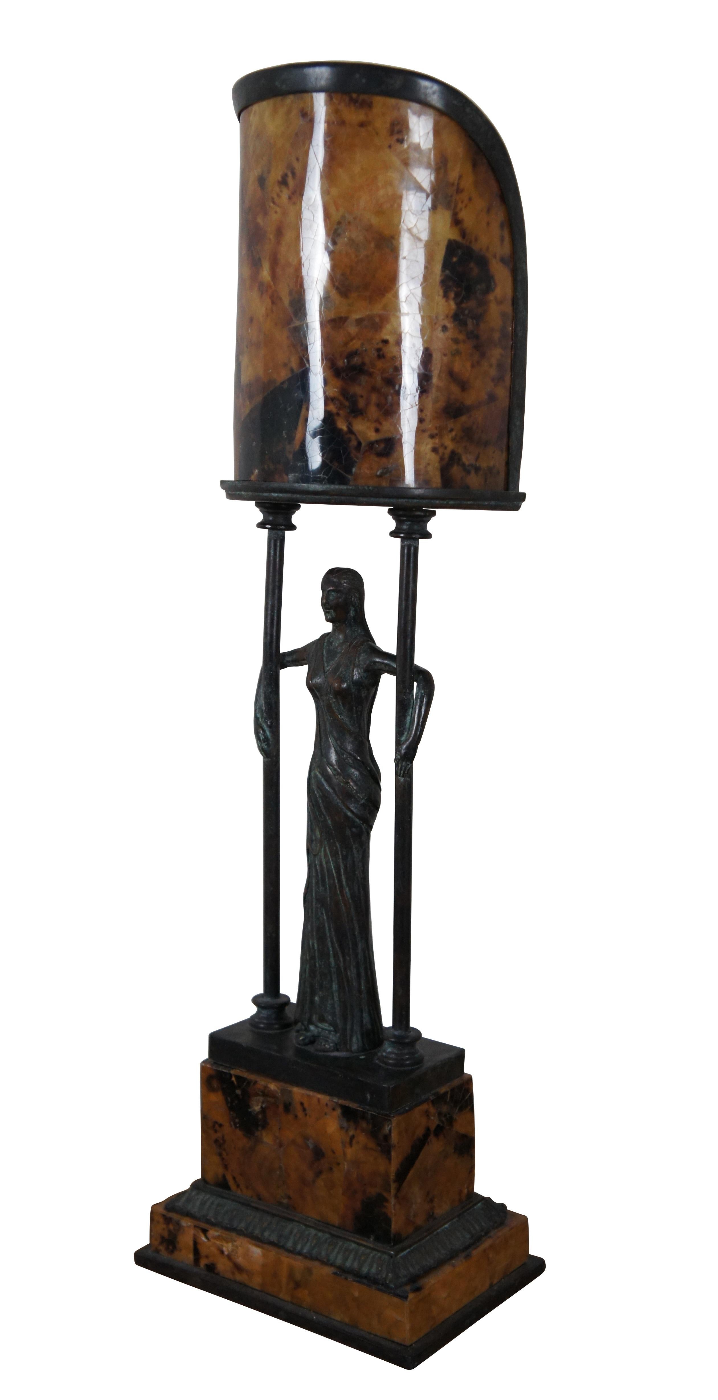 Vintage Maitland Smith table lamp featuring a bronze female figure standing on a stacked rectangular bronze and penshell base, her arms wrapped around a pair of slim pillars at her sides, beneath the canopy of a simple half-cylinder penshell shade.