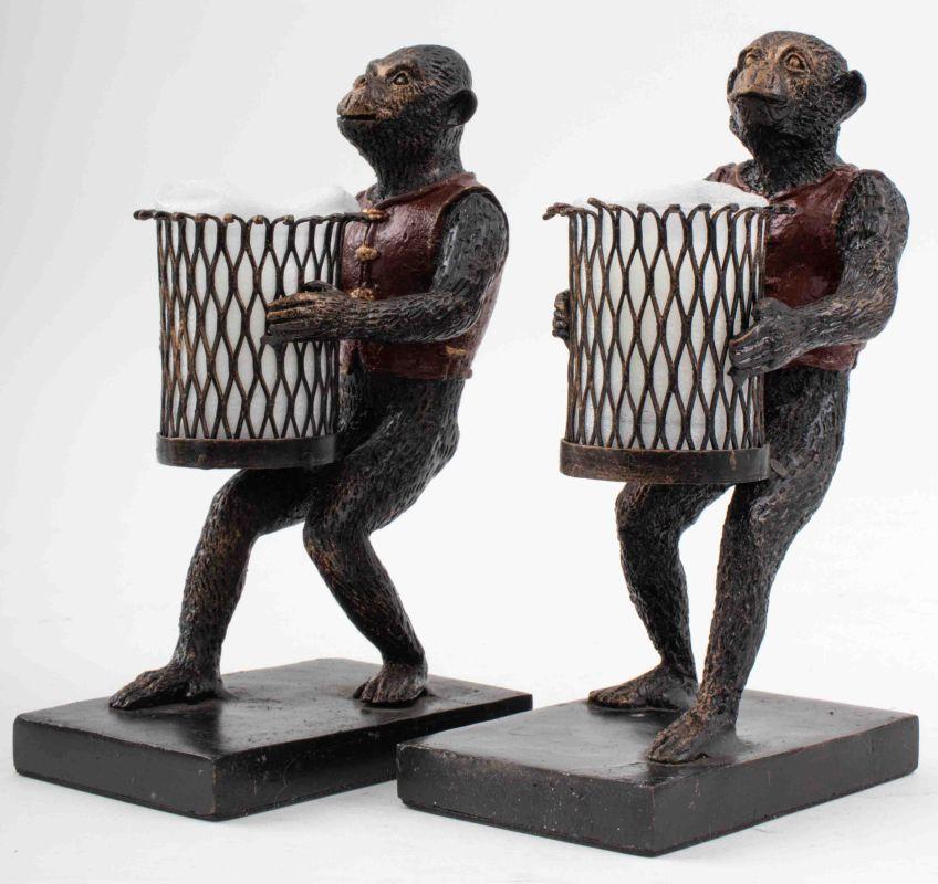 Pair of Maitland Smith Attributed Monkey-Form Cold-Painted Cast Iron Candleholder Bookends, the monkeys wearing red vests and holding iron baskets with glass candle votive within, all upon rectangular bases. 8.5