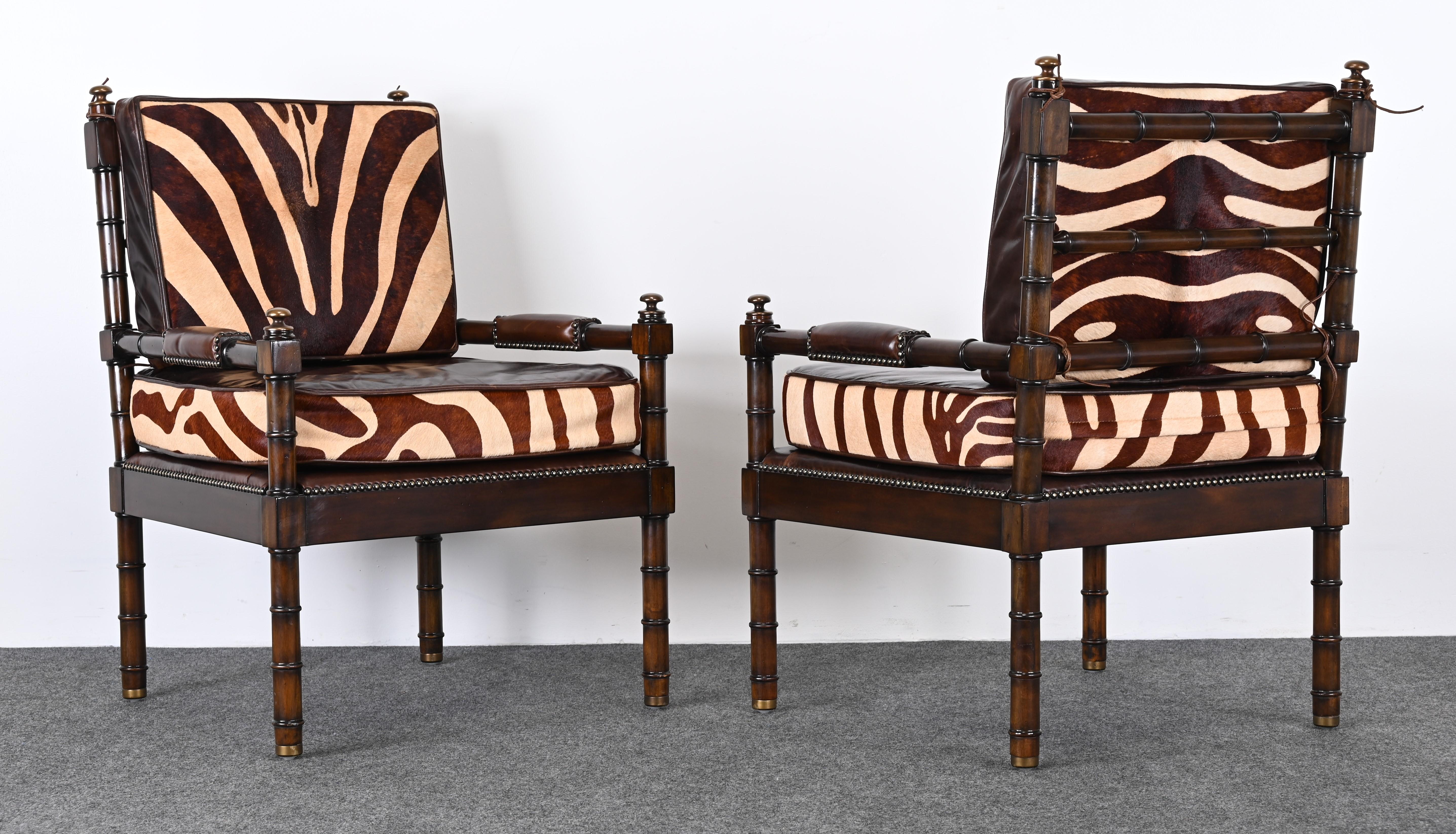 A magnificent pair of faux bamboo mahogany armchairs with leather and cowhide zebra print fabric. The chairs are accented with brass finials and rawhide detail. These chairs would work well in any traditional or contemporary setting with just a