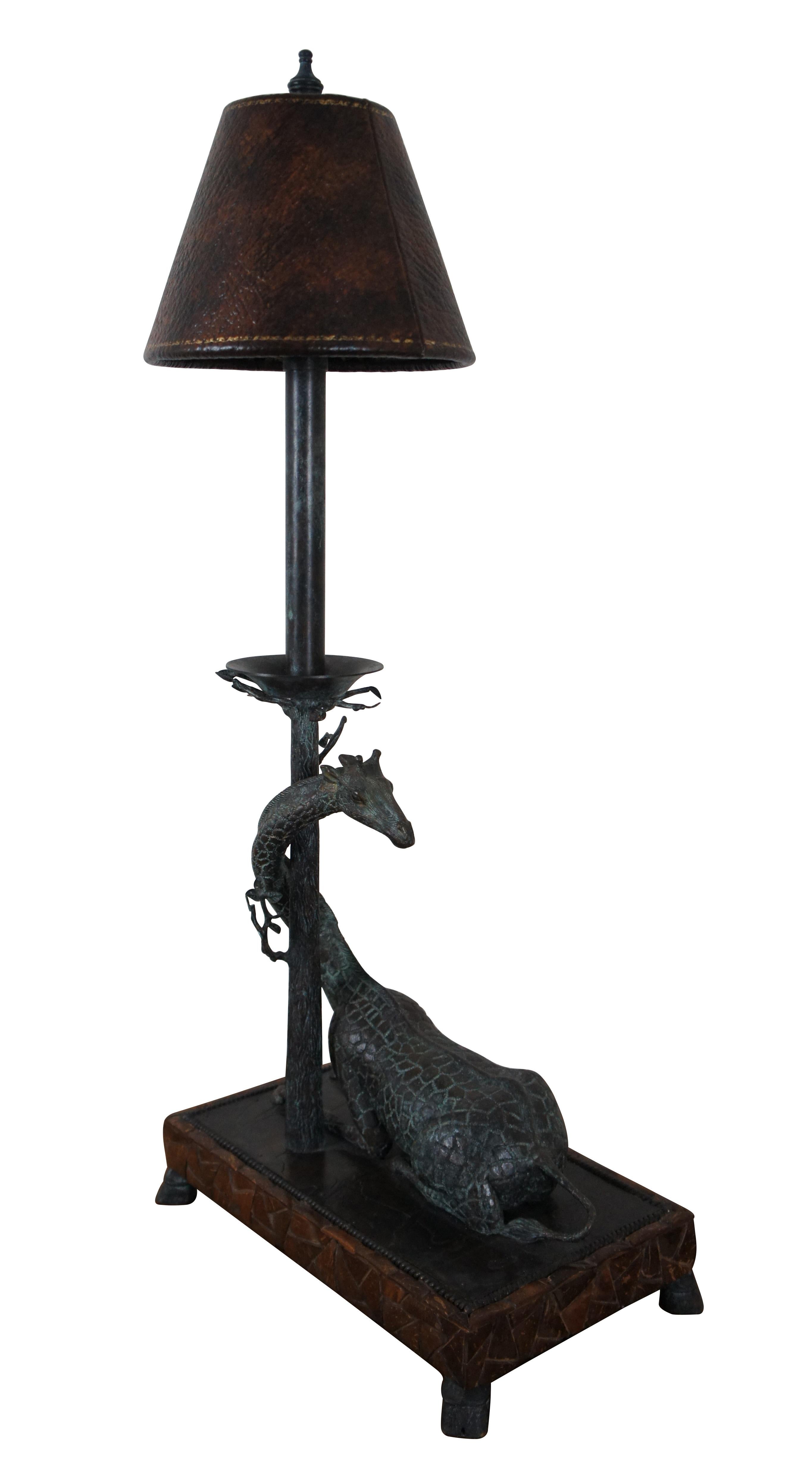 Maitland Smith table lamp, made of bronze with factory distressed patina / verdigris. Rectangular base supported by hoof feet, decorated with a coconut shell mosaic echoing the pattern of giraffe hide. On the base lays a reclining giraffe with its