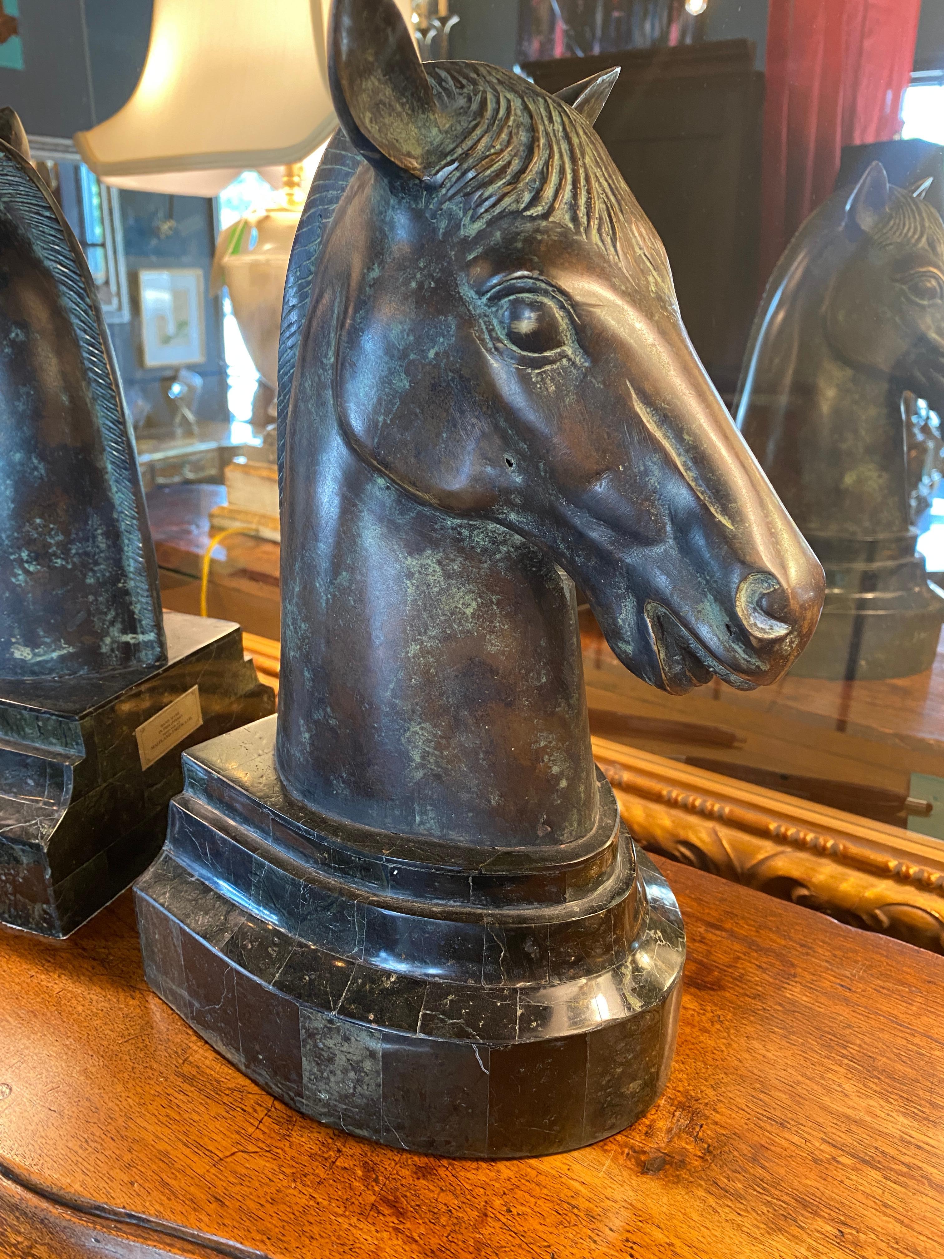 Patinated bronze horse heads mounted on granite veneered based lined with leather bottoms.