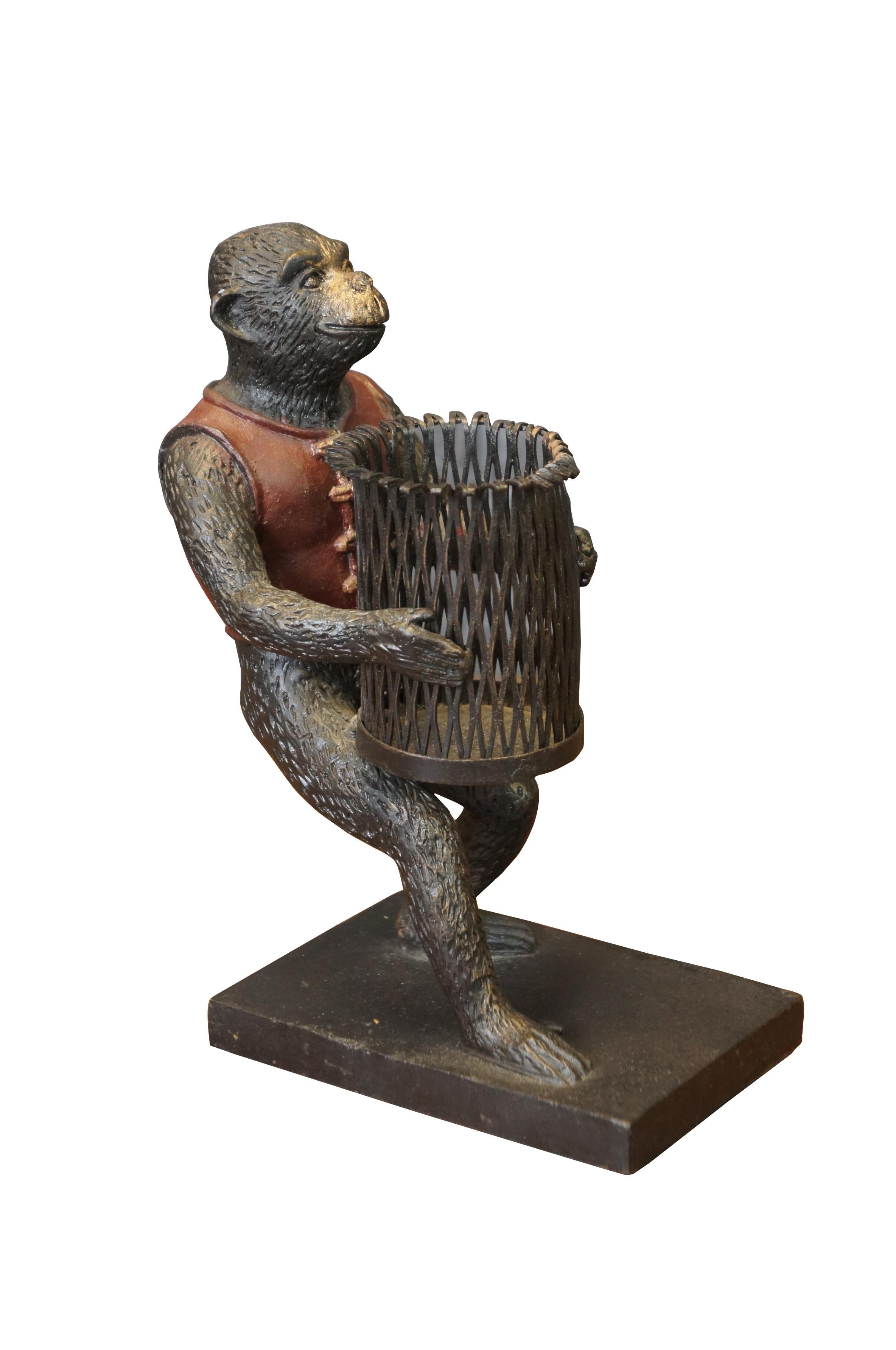 Late 20th century bronze figurine / votive candholder / toothpick / pen holder / library bookend in the shape of a monkey / chimpanzee wearing a red vest, carrying a cylindrical basket, standing on a rectangular base. Attibuted to Maitland