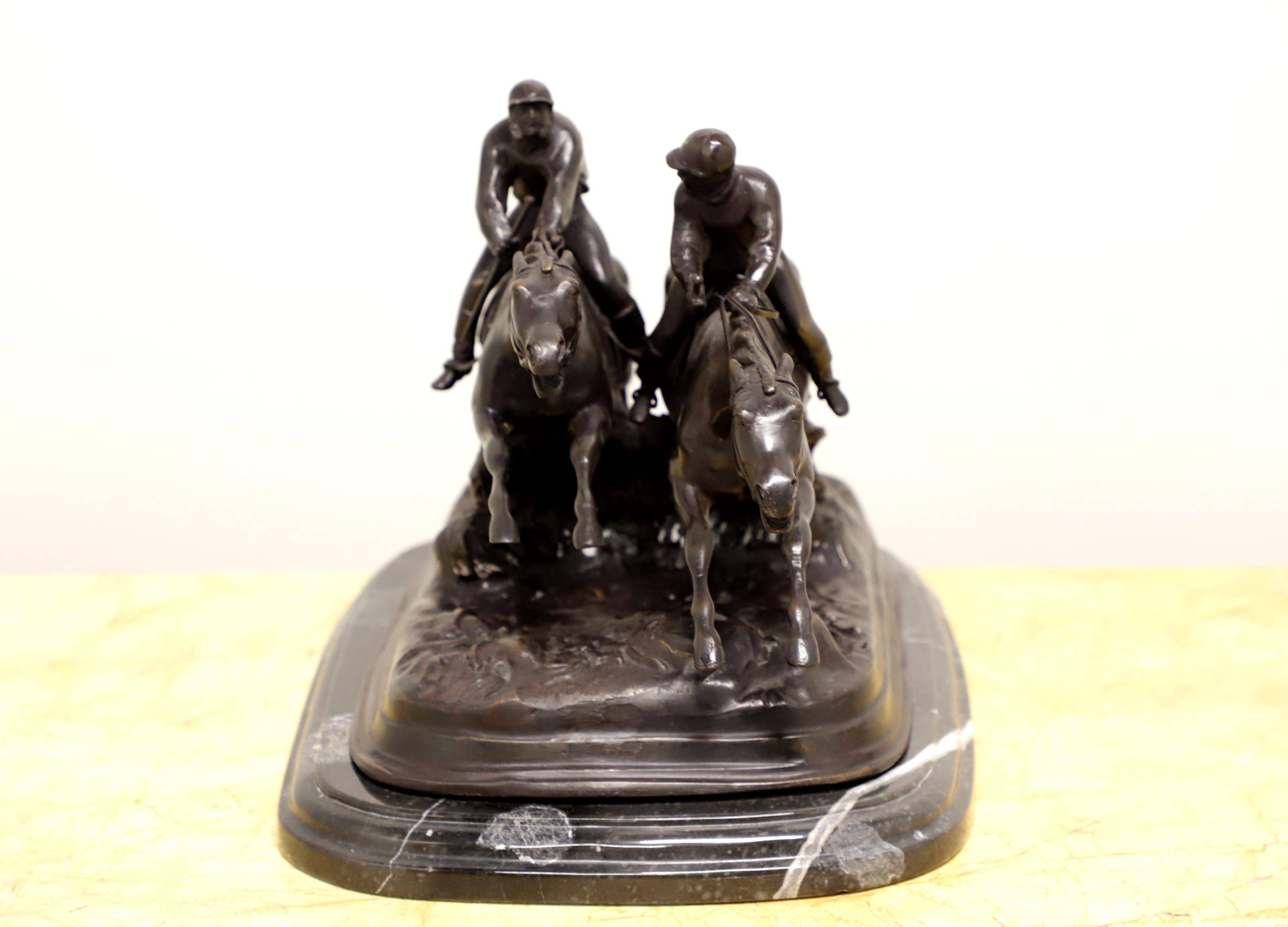 A table top sculpture in bronze depicting two jockeys on racehorses in a steeplechase race jumping an obstacle by Maitland Smith. Bronze terrain, obstacle, horses and jockeys on a marble base. Made in the Philippines, in the late 20th