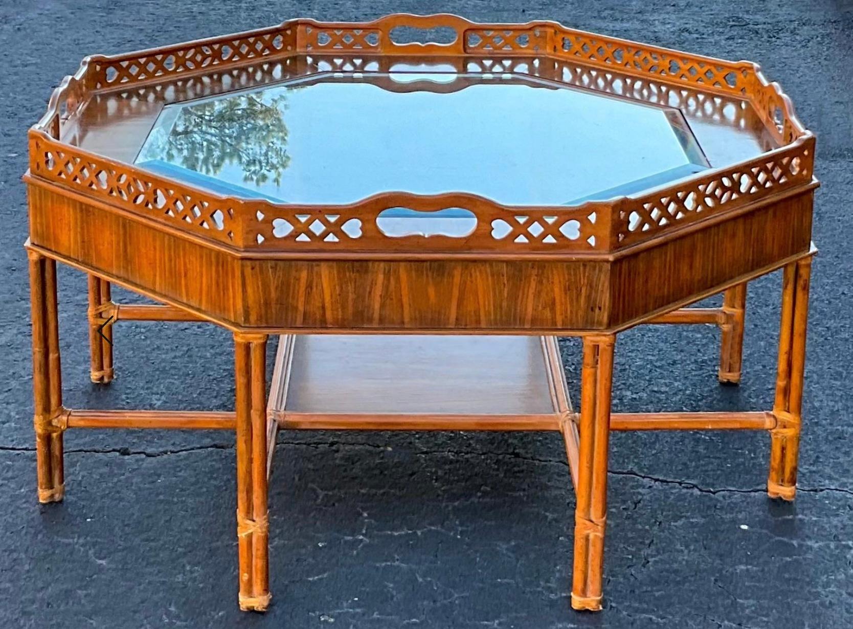 This is a late 20th century coffee table with Chinese Chippendale styling. It’s base is a woven rattan with shelf, while the top takes the form of a tray table. It is by Maitland-Smith and in very good condition.