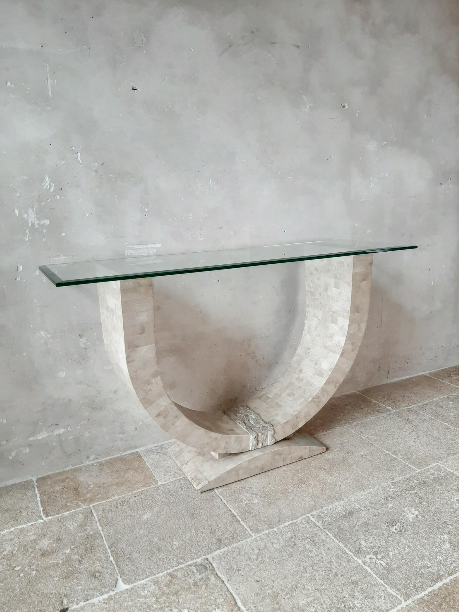 Maitland Smith designer tesselated console table with a bevelled glass top. The base is with travertine veneered wood which makes the piece movable. 

Dimensions: H 81 x W 135.5 x D 40 cm.
 
