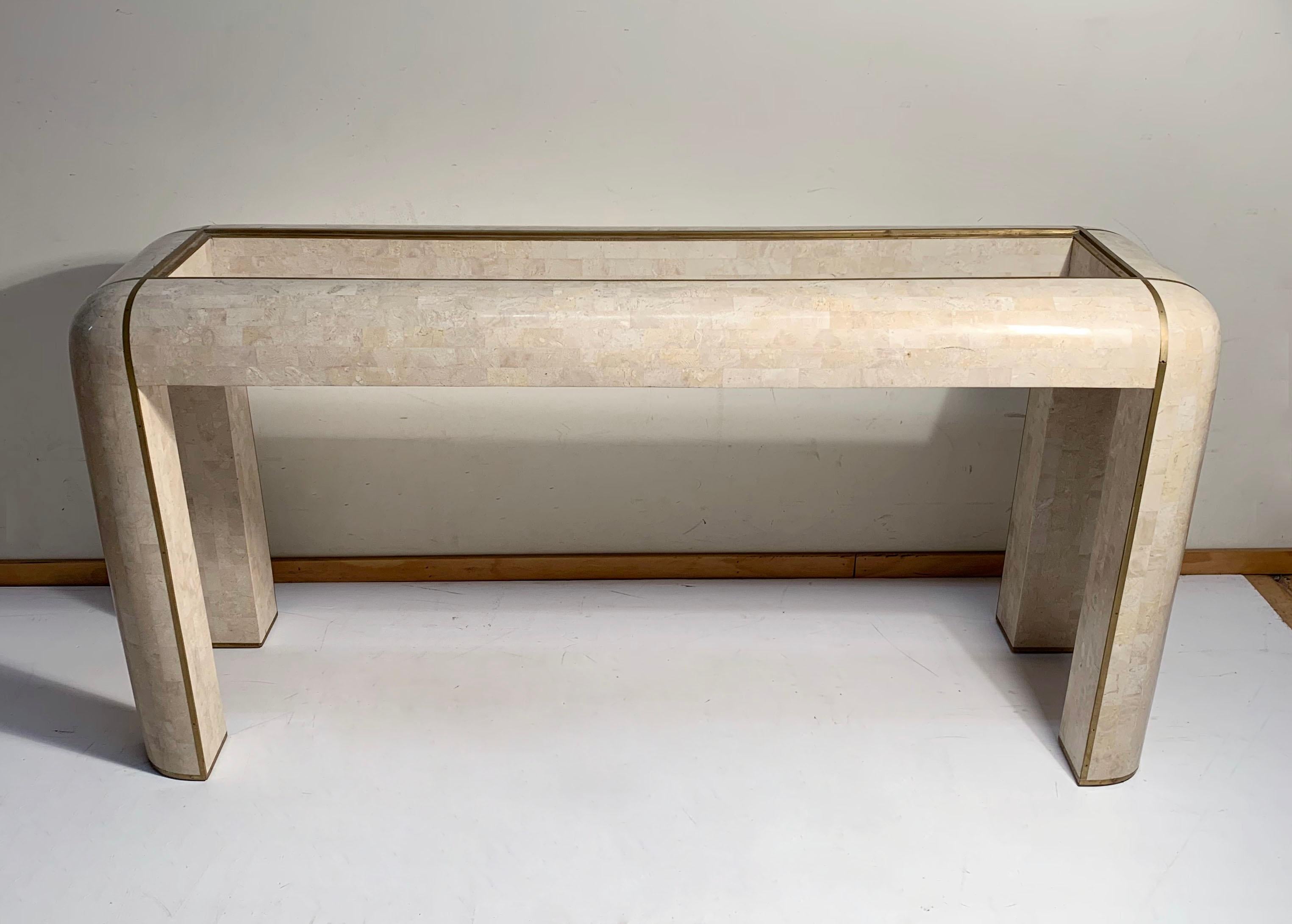 Maitland Smith console tessellated fossil mosaic stone marble console table.
Exceptional form with a beautiful cream/ivory color stone veneer. Brass inlay. In the manner of Karl Springer and Gabrielle Crespi.

A few areas that can use a repair.