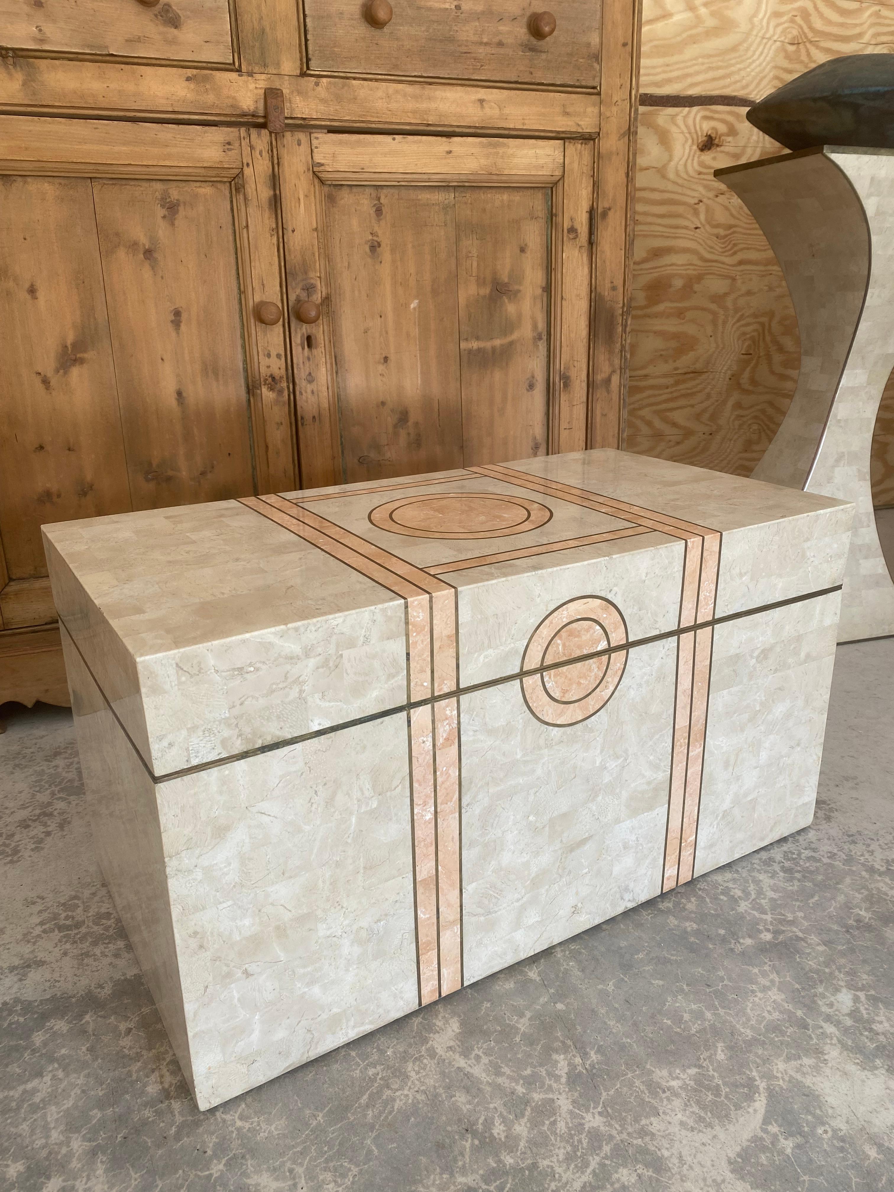 Coral and pink coral set in an Art Deco influenced geometrically oriented inlaid design. The brass trim is patinated naturally from age, and the interior is wood-lined for storage of a selection of blankets or throws.

While this piece is most often
