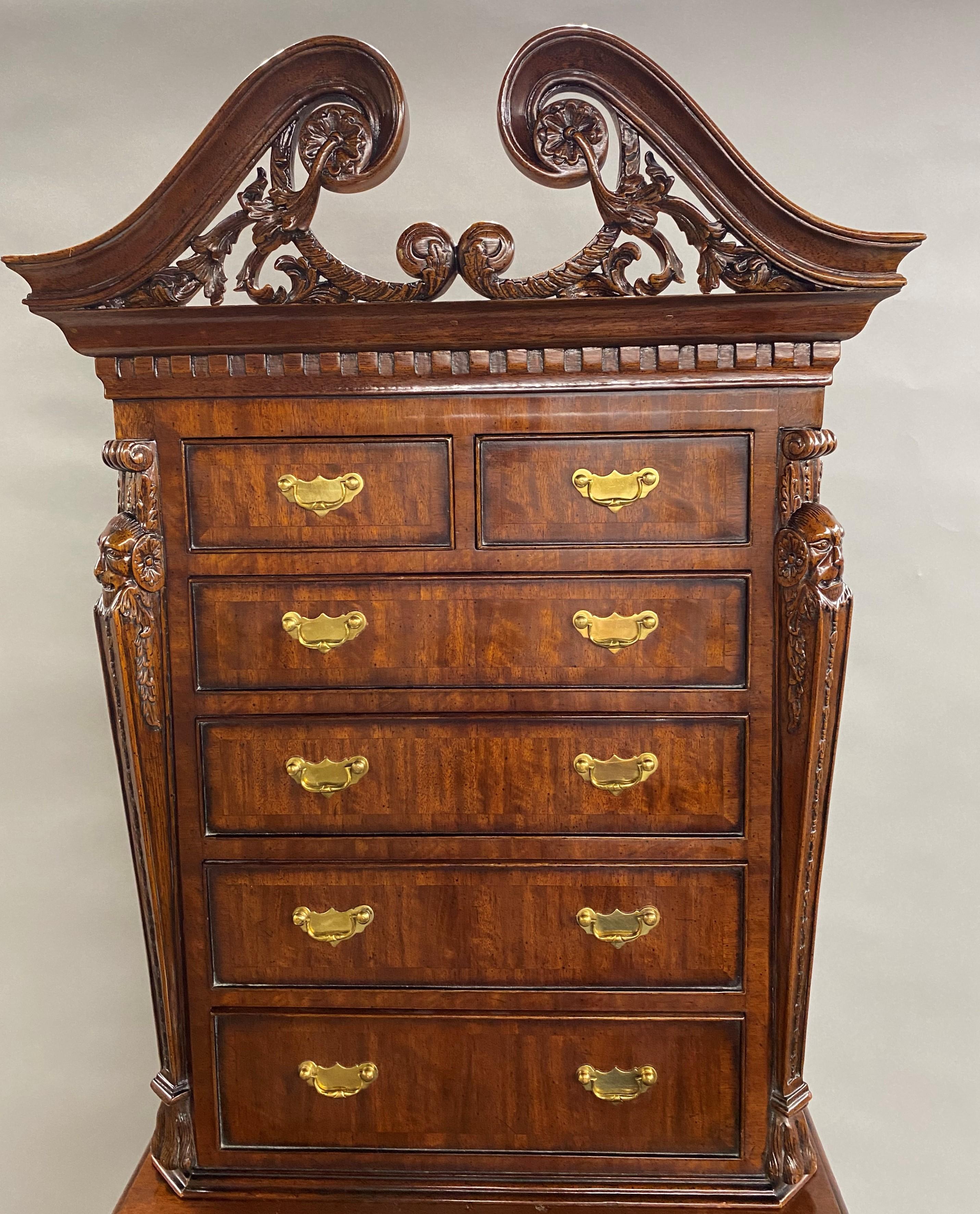 A wonderfully carved mahogany two part diminutive chest on chest or jewelry / valuables chest by Maitland Smith with a swan’s neck split pediment with scrollwork and rosettes surmounting an upper case with a two over four drawer configuration, on a
