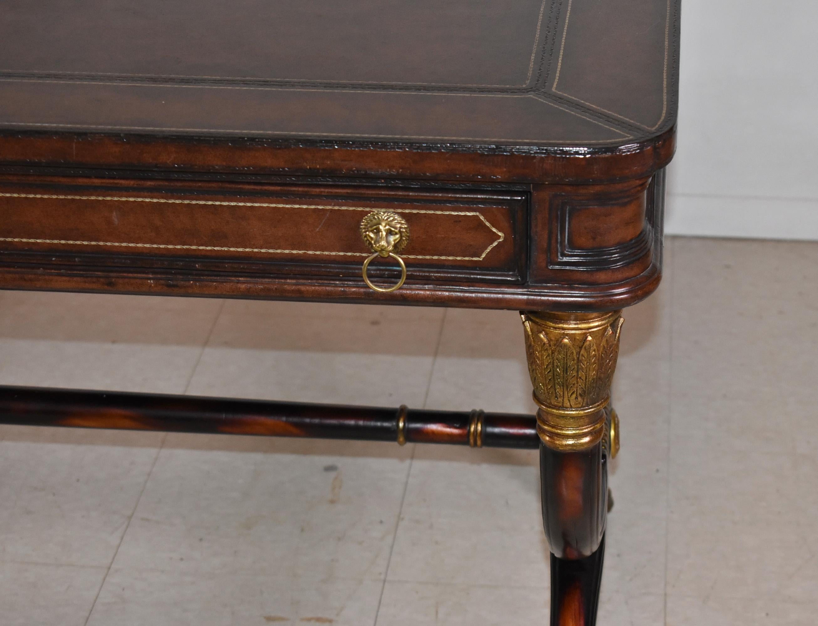 Maitland Smith Schreibtisch im Empire-Stil mit geprägter Lederplatte und geschwungenen Ecken, 2 schmalen Schubladen mit Löwenzügen, Curule-Beinen mit vergoldeten Akanthuskapitellen und Tatzenfüßen. Etwas Sonne verblasst. 60