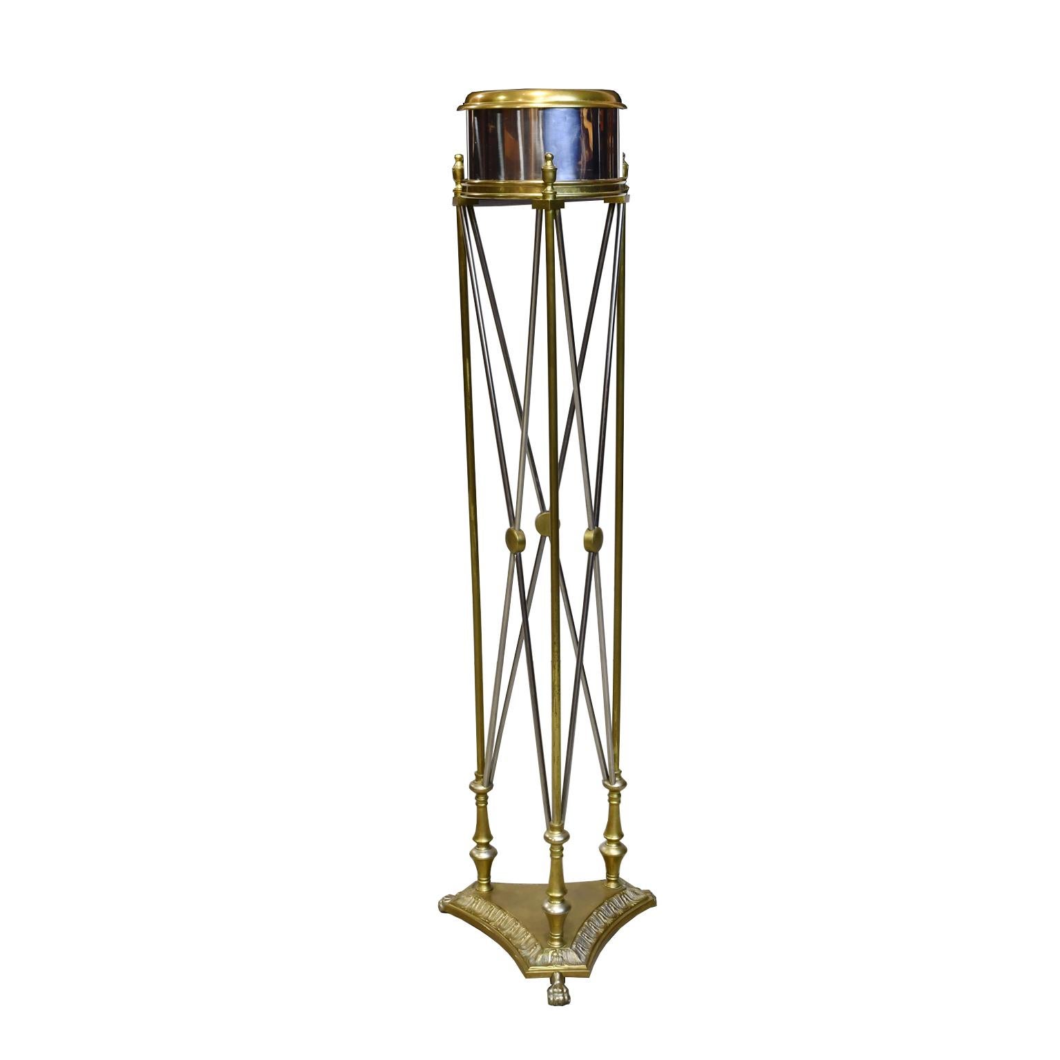 A very handsome vintage jardinière in the Empire style manufactured by Maitland Smith in the 1980s with cylindrical polished-chrome planter trimmed with brass over a cast and fabricated base that is embellished with intersecting rods in chrome and
