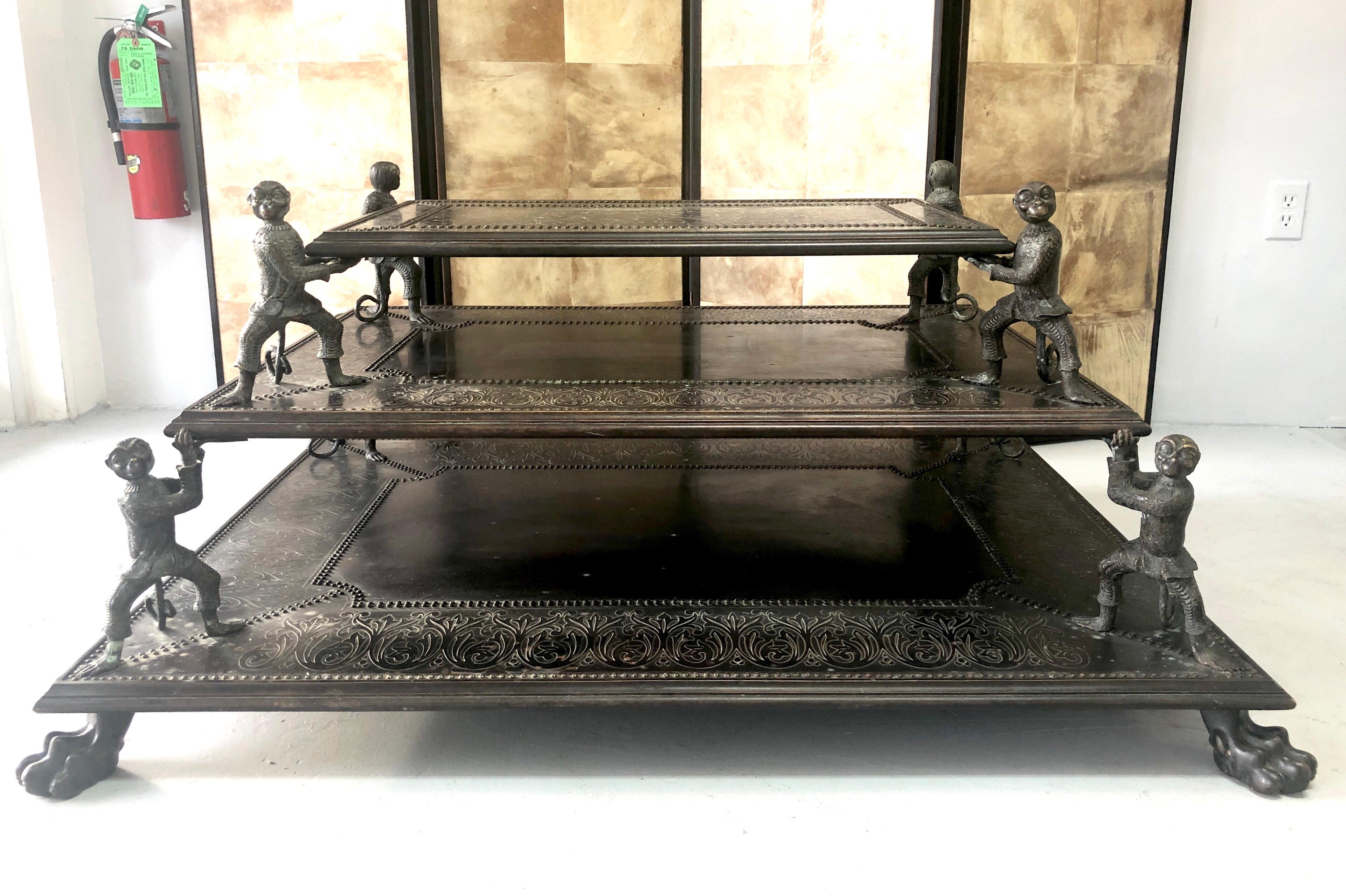 Extraordinary bronze table, 3 tiers, the bottom tier i supported by large hairy paws, the upper 2 levels are held by bronze monkeys with great personalities. The surfaces are embossed bronze with small nail detail.