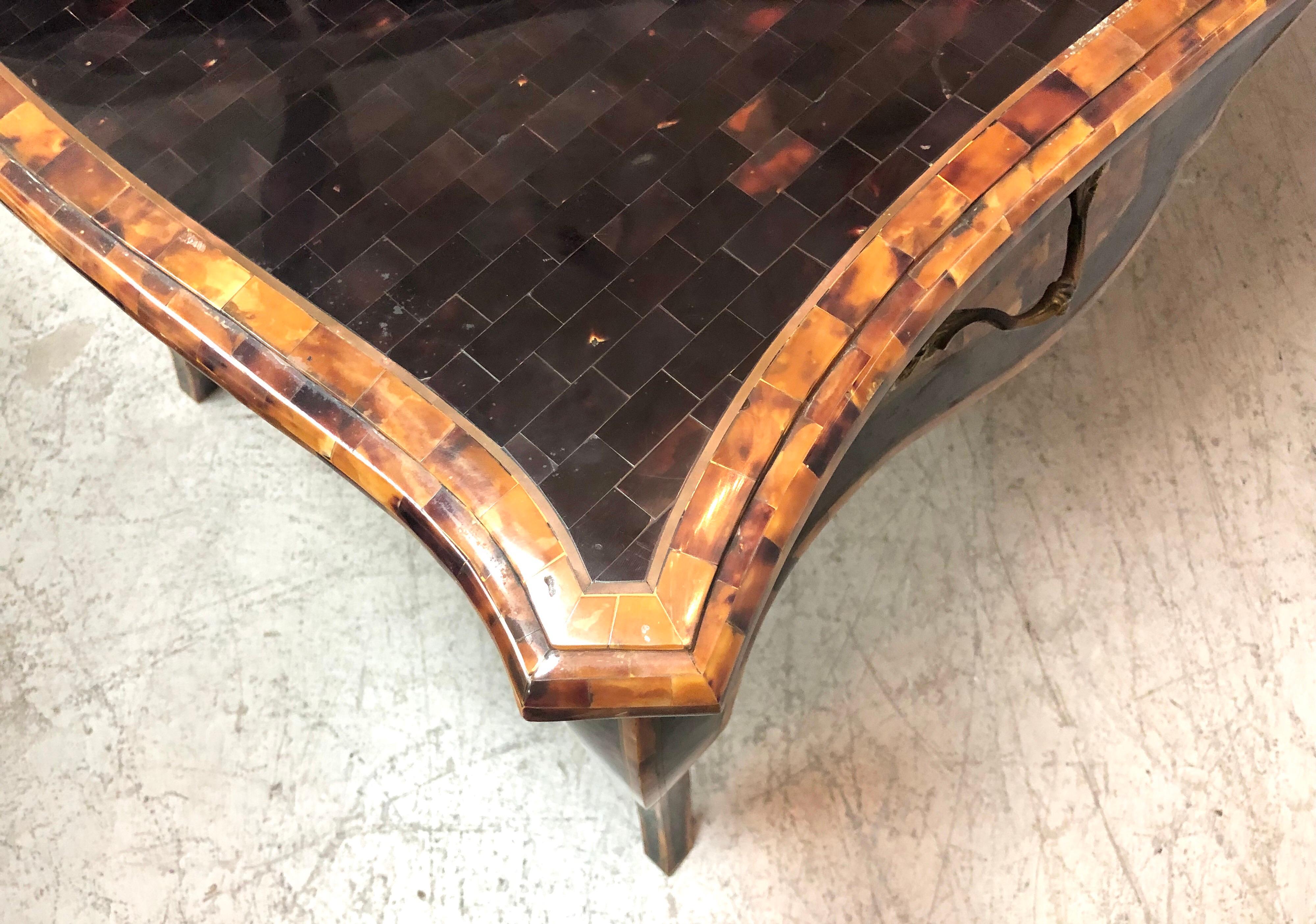 Stunning desk by Maitland-Smith. All the surfaces are done in a tessellated stone that resembles tortoise shell, there are also bands of brass in between the areas of different tones. 3 drawers, there is also a small secret compartment that is