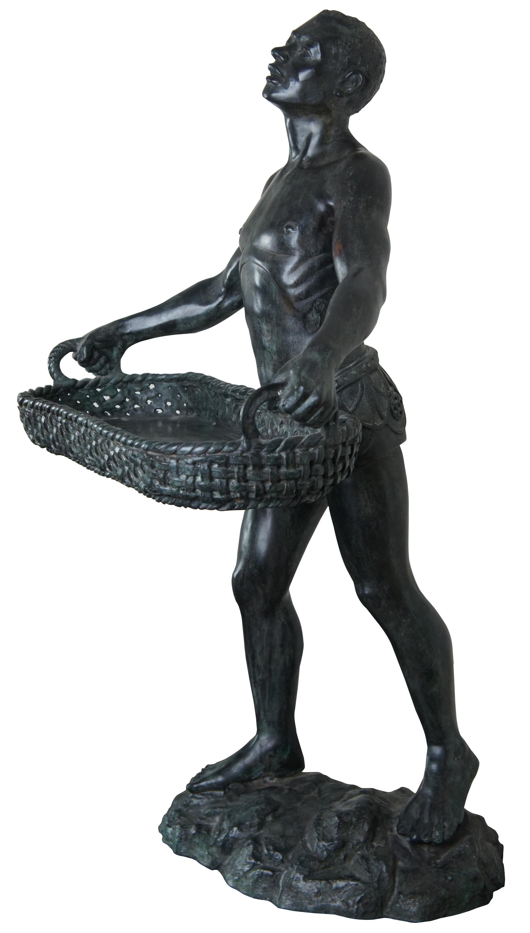 Maitland Smith figural bronze statue, late 20th century. Features a toned African man in ancient Greek inspired lower garment holding a woven basket. Marked along underside. Perfect for use as dumbwaiter, stand or to hold your curiosities.
 