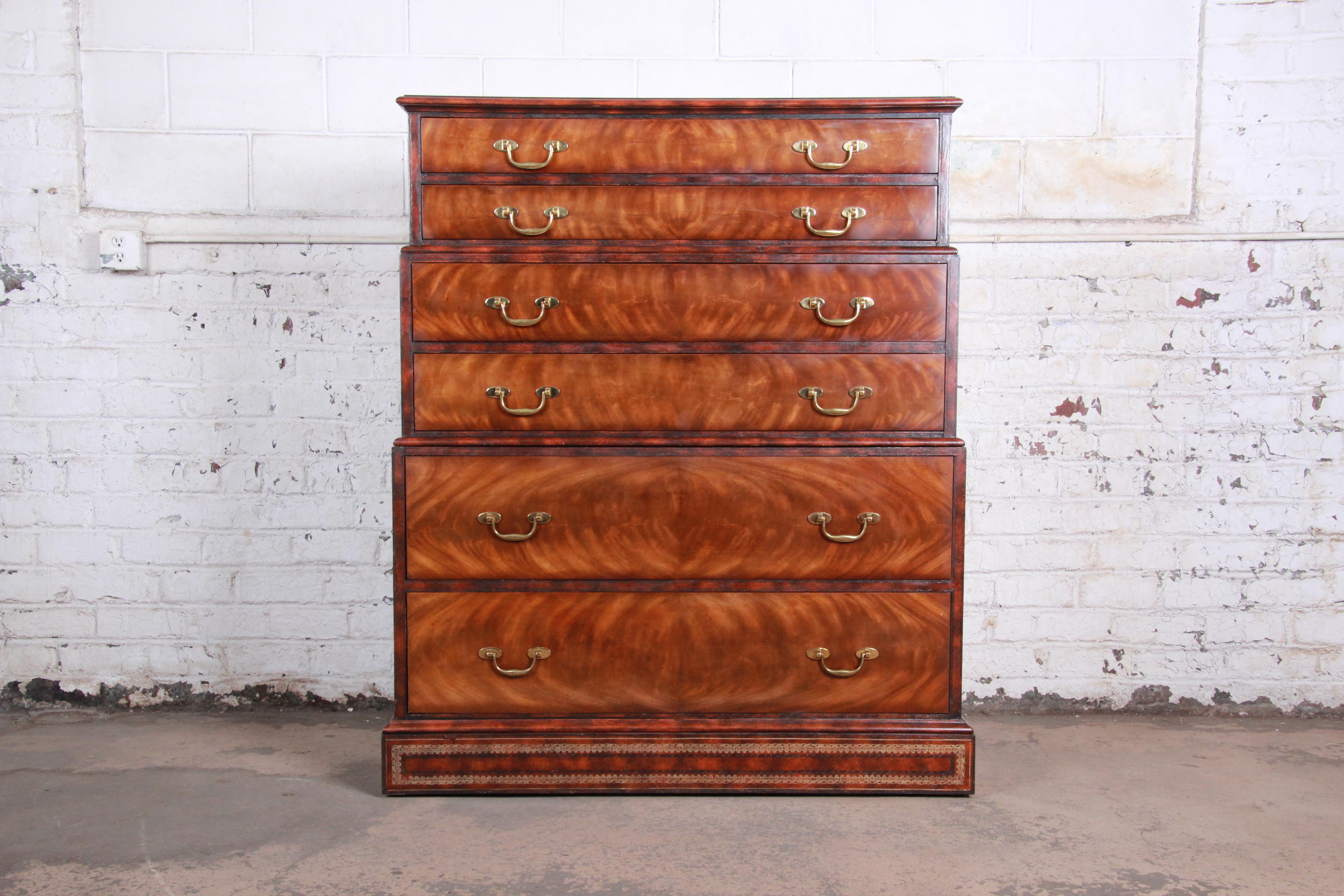 An exceptional chest on chest highboy dresser by Maitland Smith. The dresser features stunning flame mahogany wood grain with a beautiful tooled leather top, sides, and base. It offers ample storage, with six drawers. Brass hardware is original, and